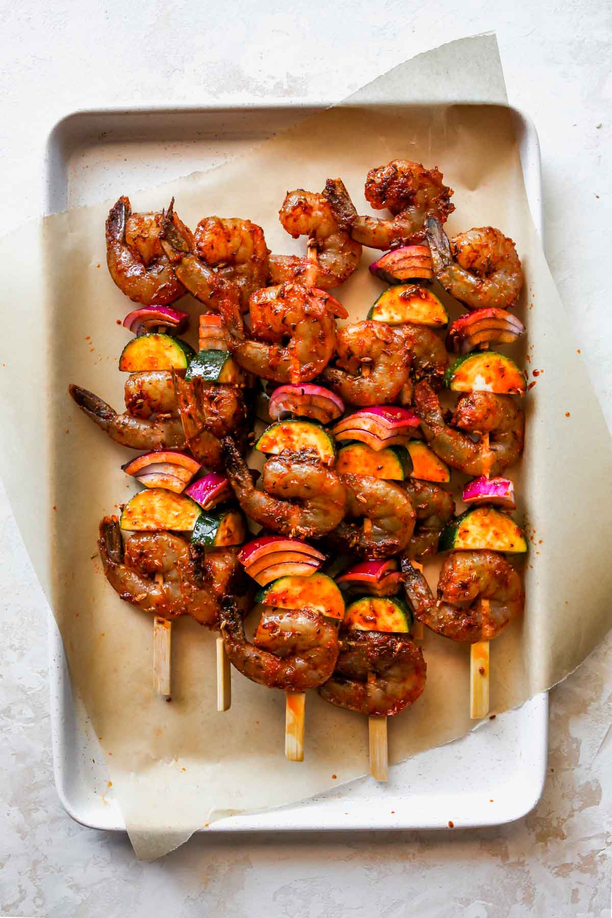 Marinated prawns, zucchini, and red onion threaded on wooden skewers