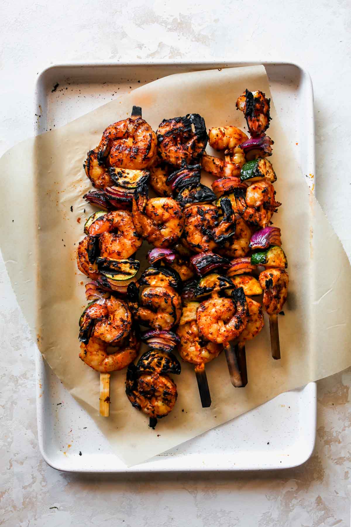 Grilled shrimp kebabs on a parchment-lined baking sheet