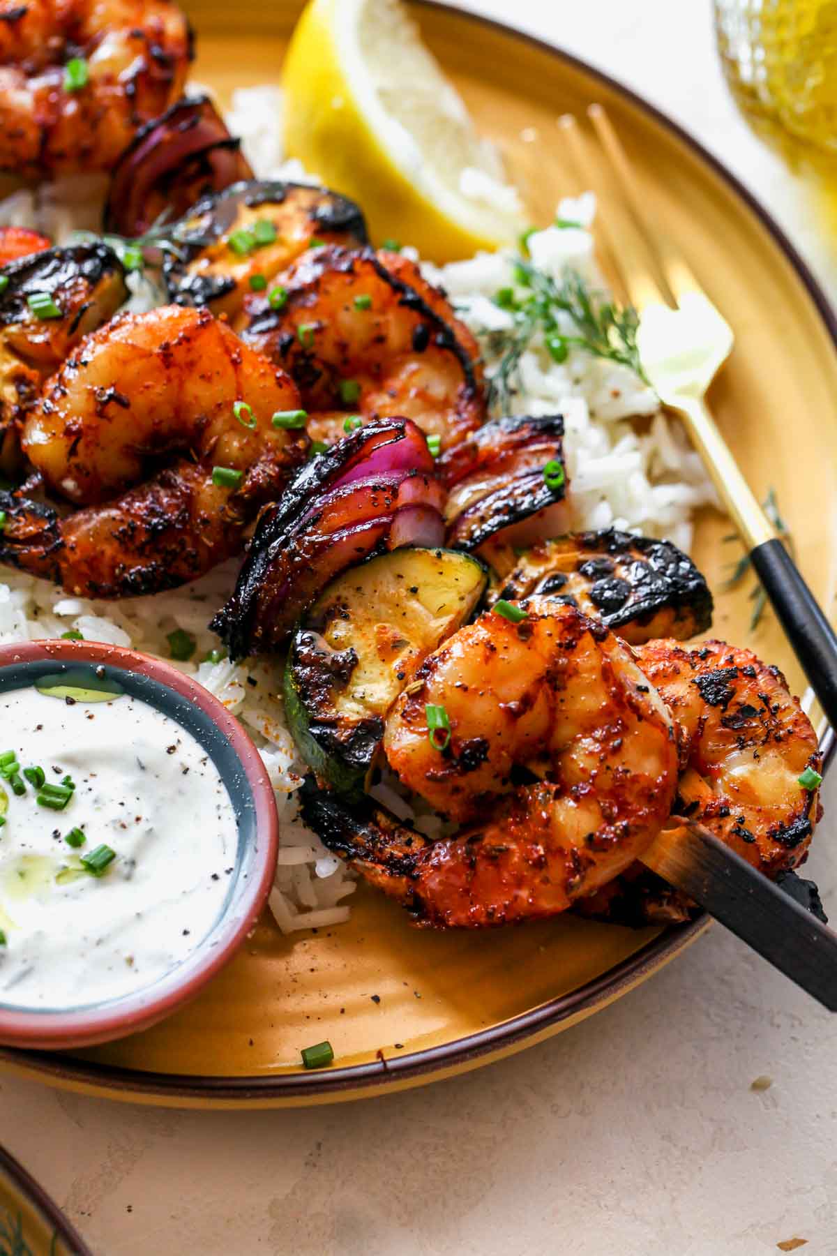 Greek shrimp kebabs on a yellow plate with rice