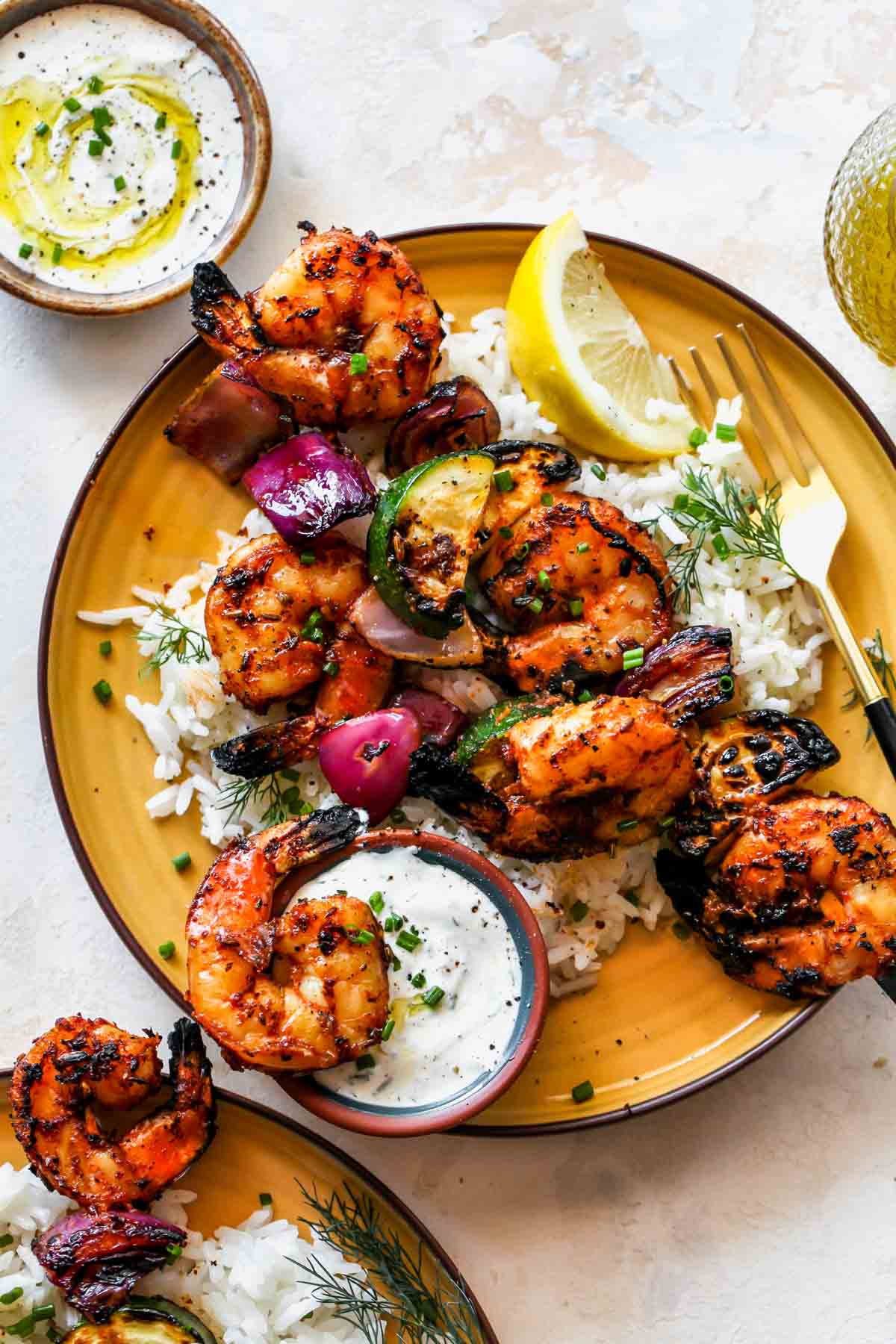 Shrimp kebabs on a bed of rice with a side of creamy sauce