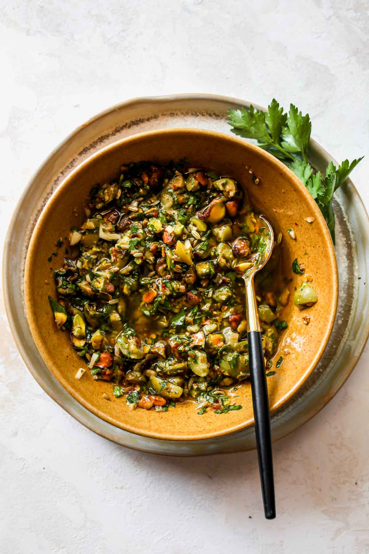 Olive-pistachio salsa being mixed in a gold bowl