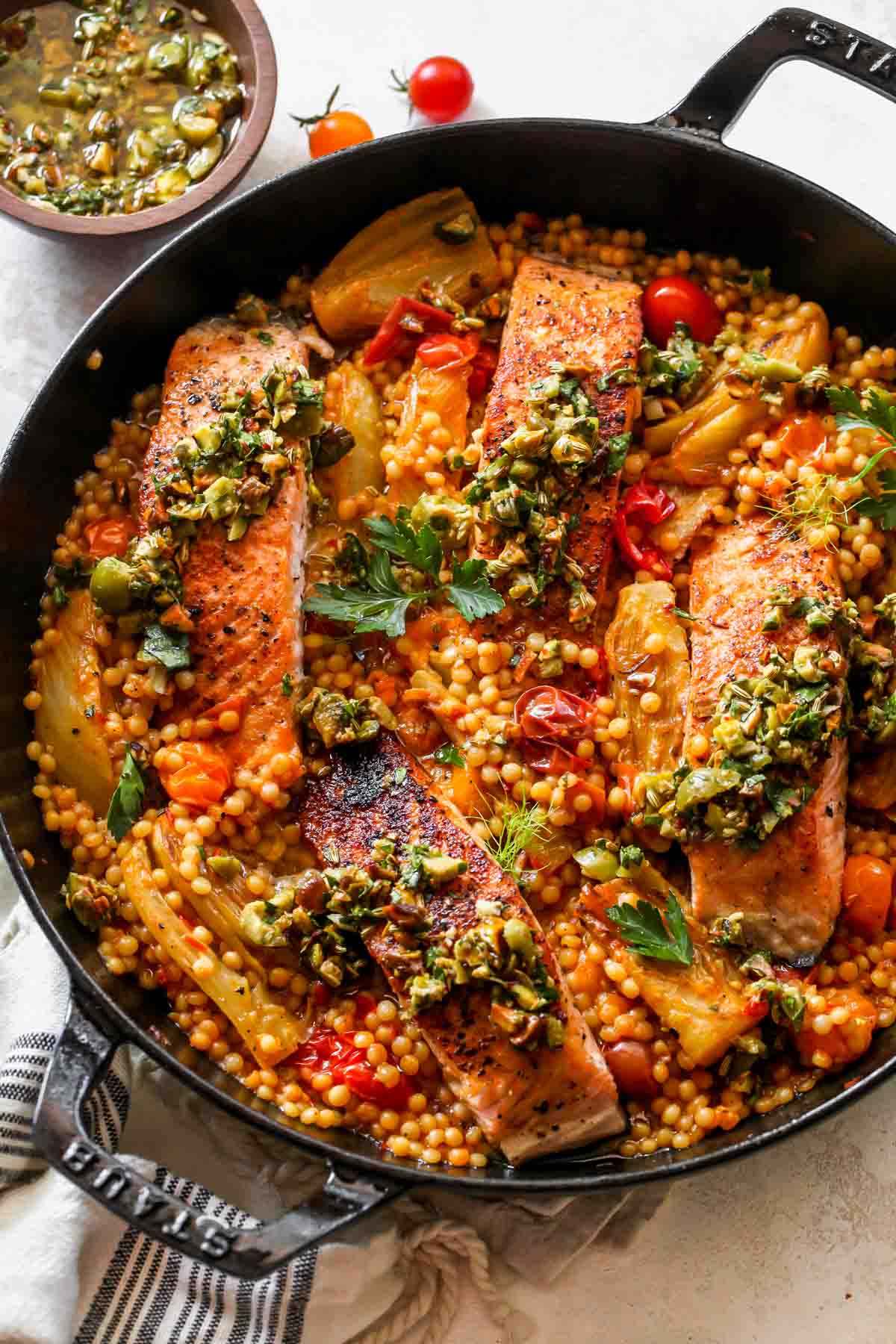 Salmon over couscous in a skillet topped with olive salsa