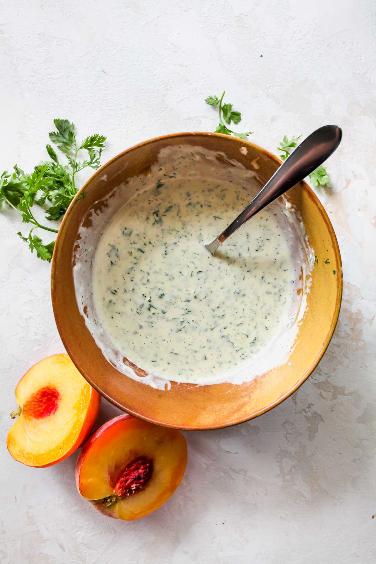 Cilantro, yogurt, mayo, and olive oil being whisked in a gold bowl