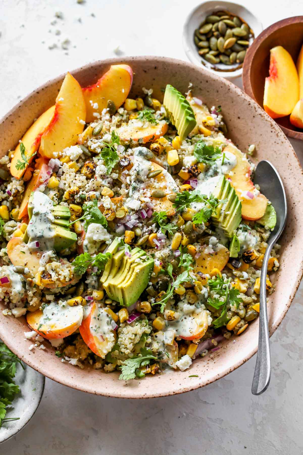 Quinoa salad with peaches, corn, and cilantro dressing in a pink bowl