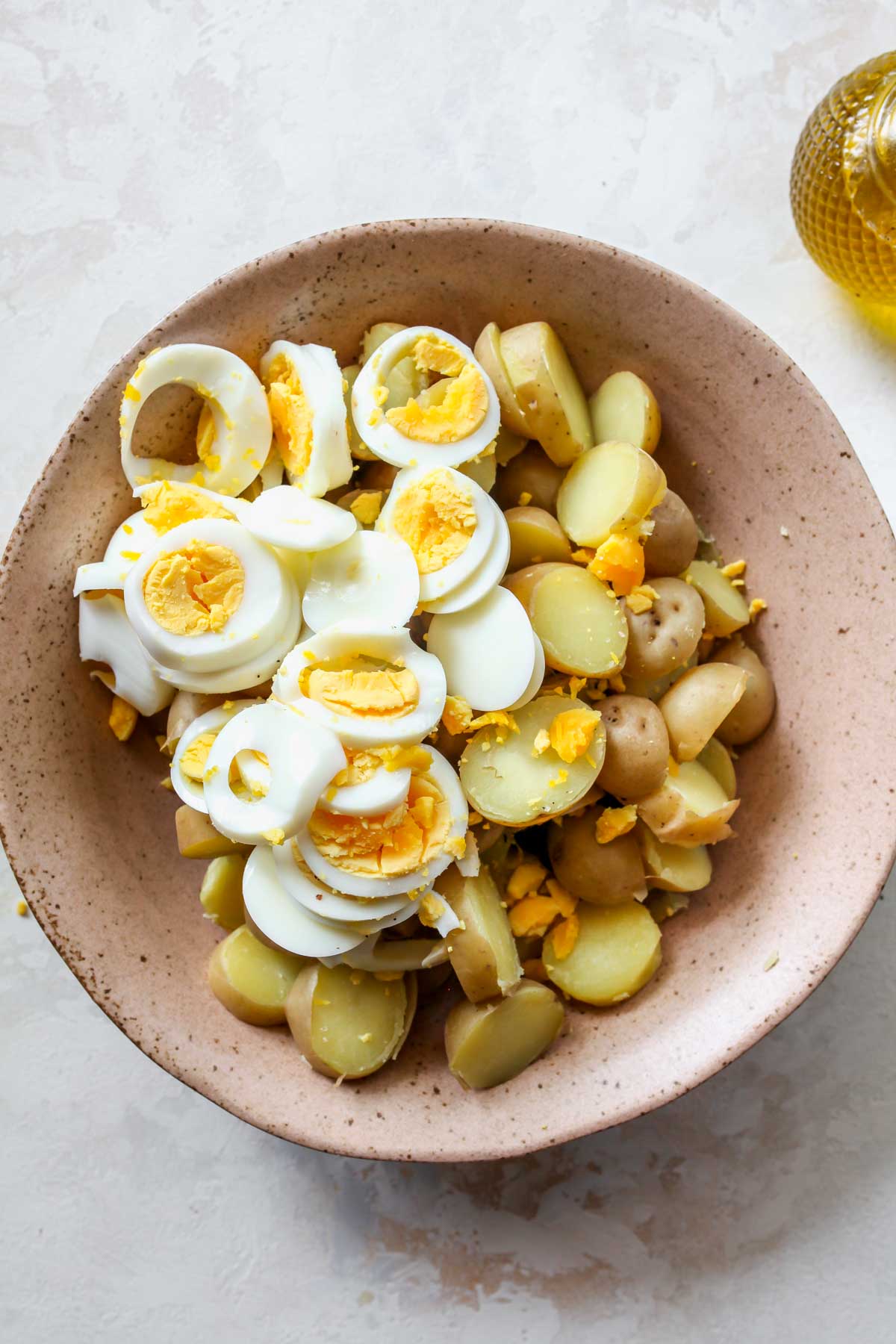 Sliced, hard-boiled eggs being added to salad