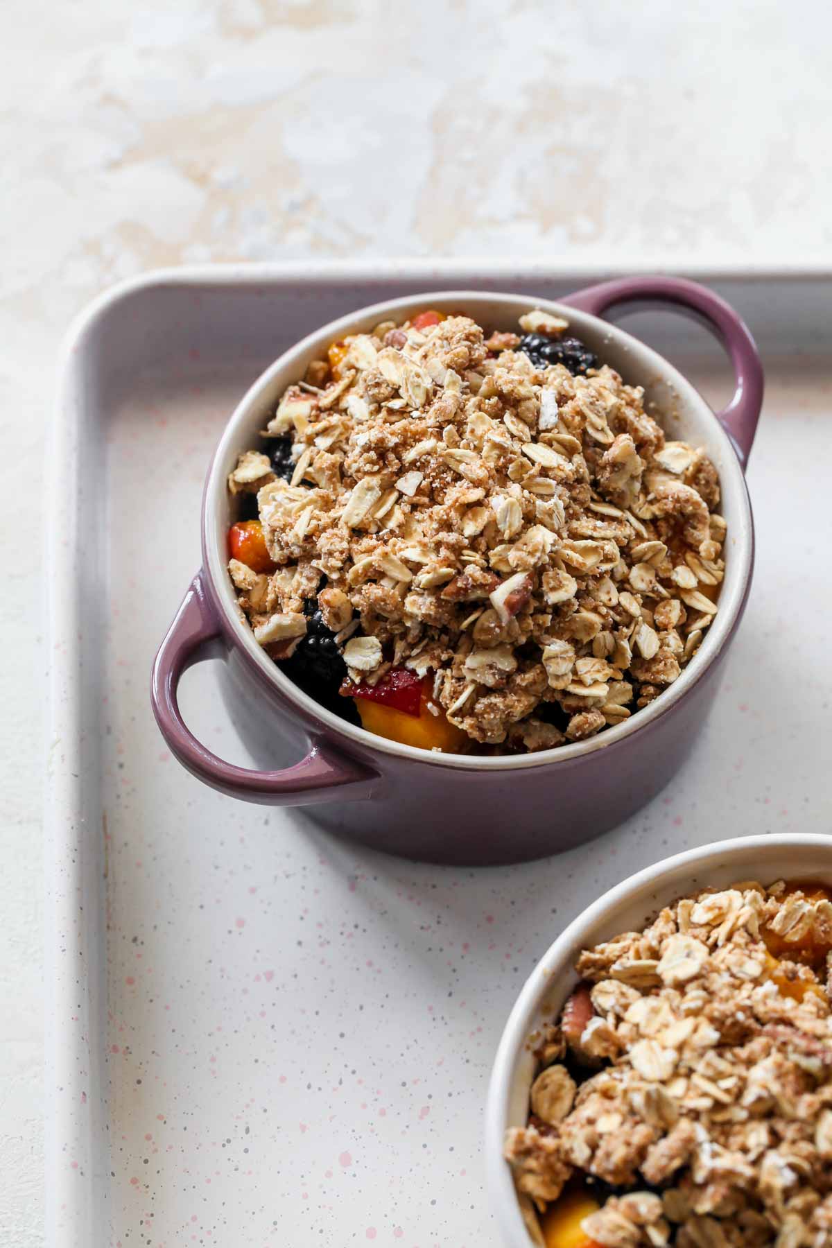 A mini ramekin filled with fruit mixture and oat topping