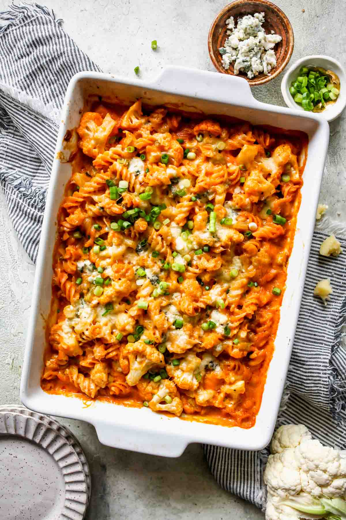 Baked buffalo cauliflower mac and cheese in a white pan on a grey surface