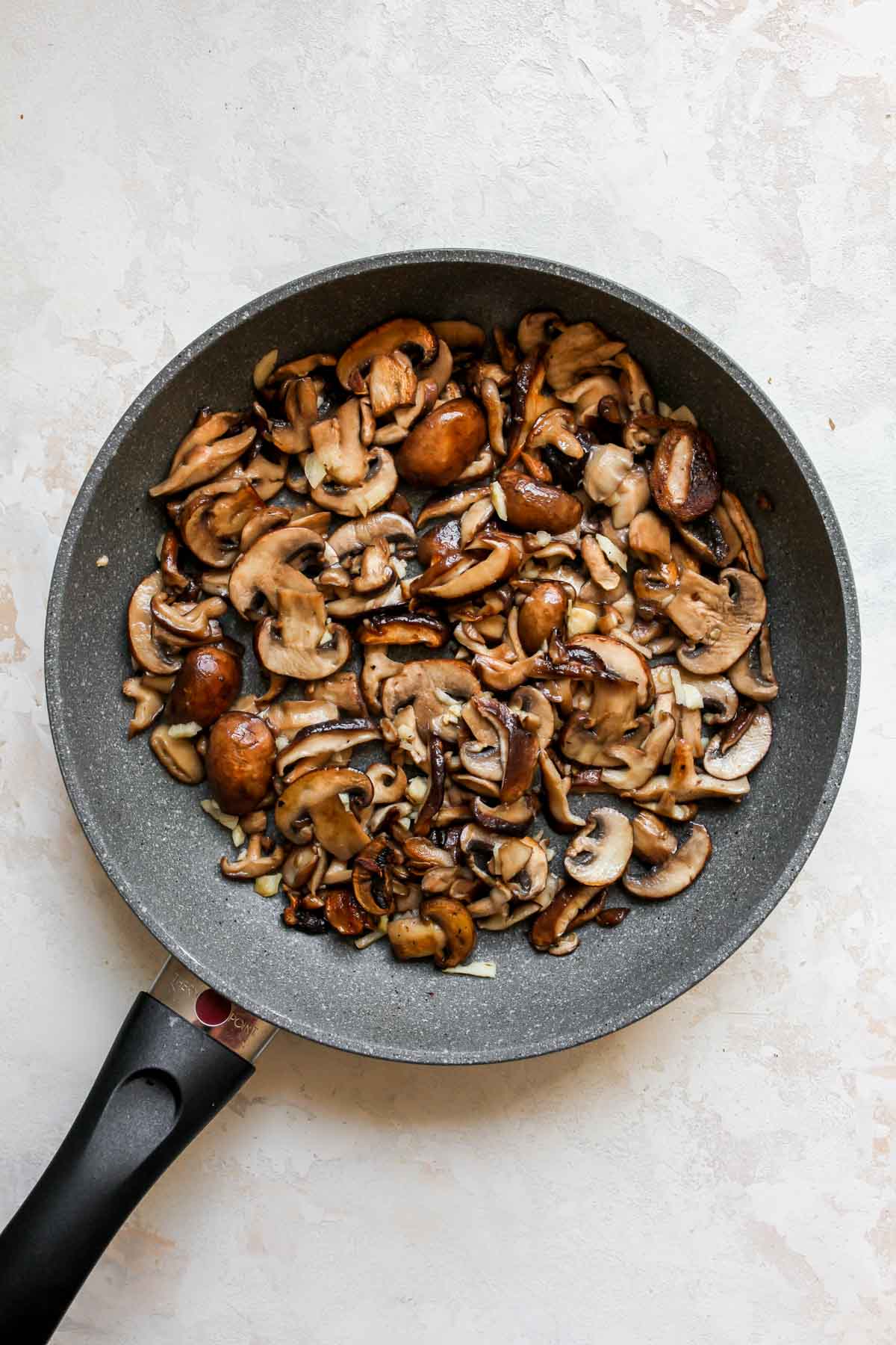 Shiitake and baby bella mushrooms sautéing in a skillet