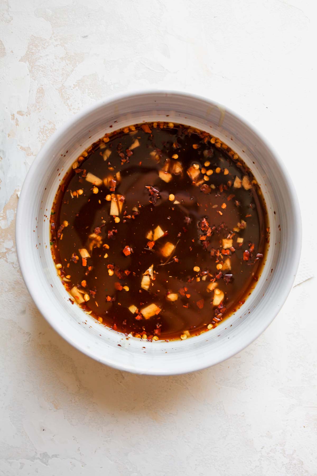 Soy sauce, broth, chili flakes, garlic, and corn starch being whisked in a bowl