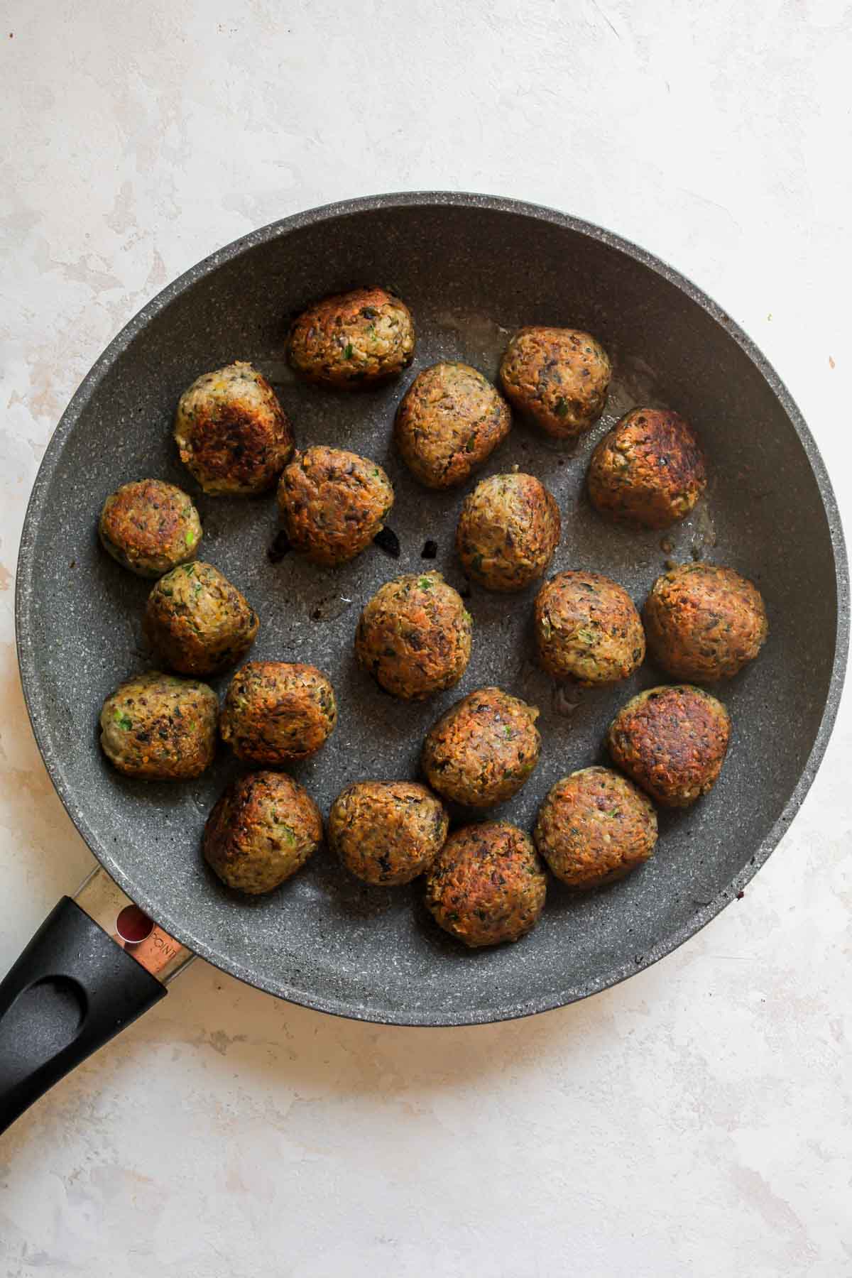 Mushroom meatballs being sautéed in a skillet