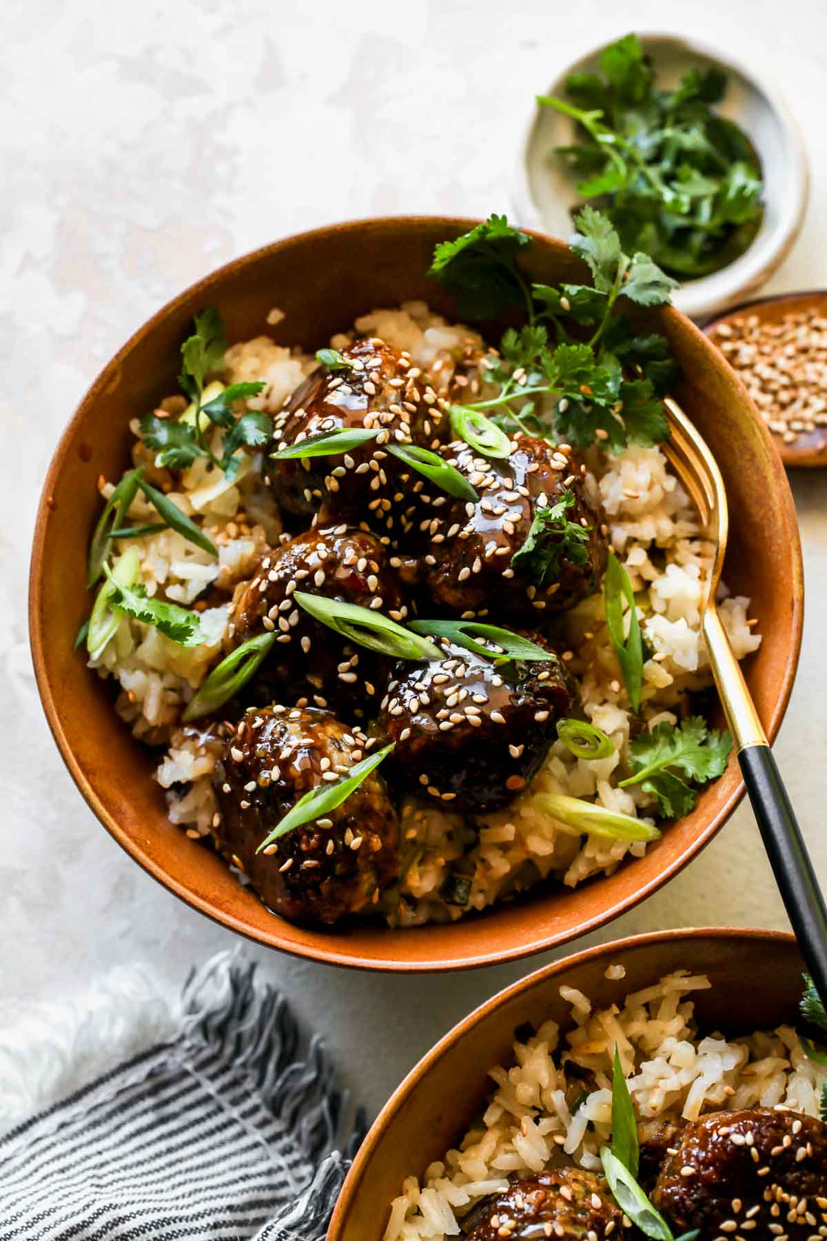 Mushroom meatballs over white rice in a gold bowl topped with scallions