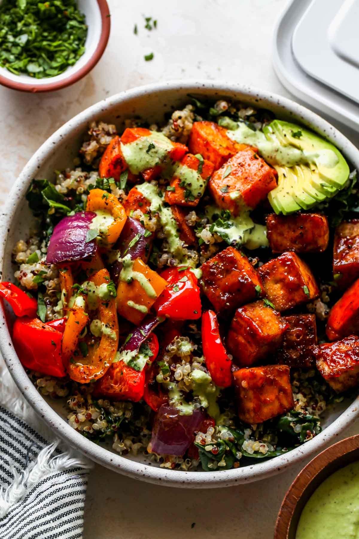 Sheet pan tofu bowls filled with quinoa, kale, roasted veggies, and green sauce