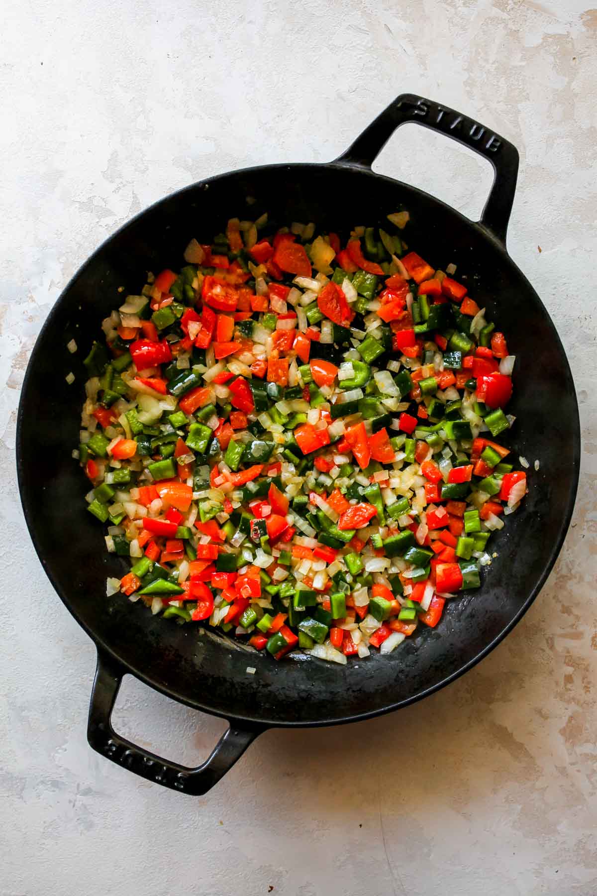 Onion, poblano pepper, and red bell pepper sautéing in a skillet