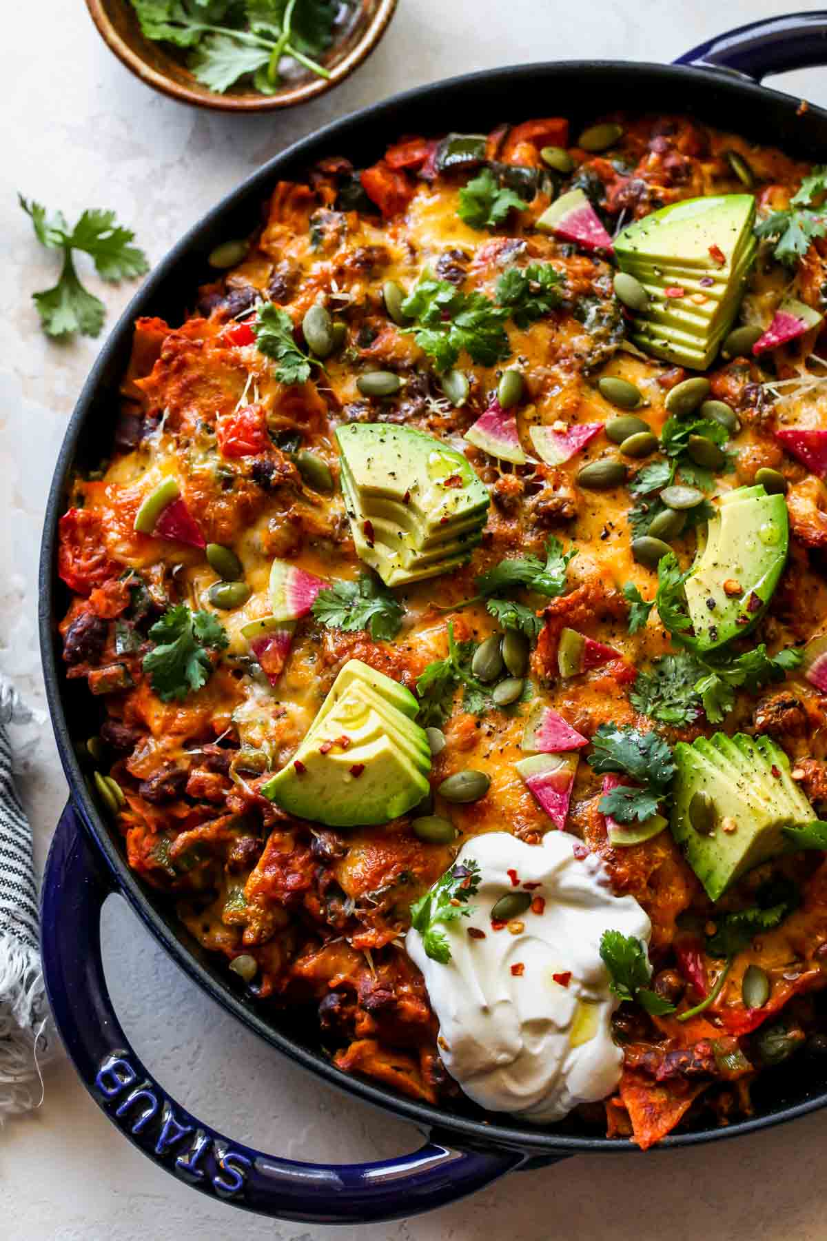 Skillet pumpkin enchiladas topped with avocado and cilantro