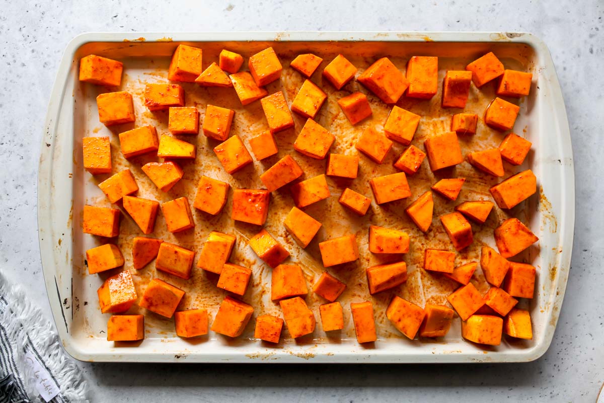 Cubes of butternut squash arranged on a rimmed baking sheet