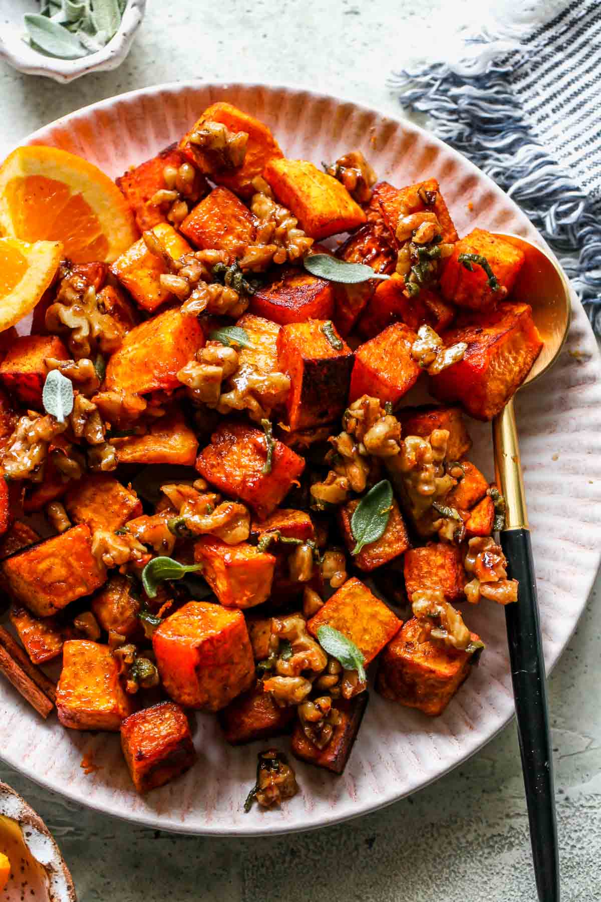 A serving spoon resting on the side of a plate of roasted squash