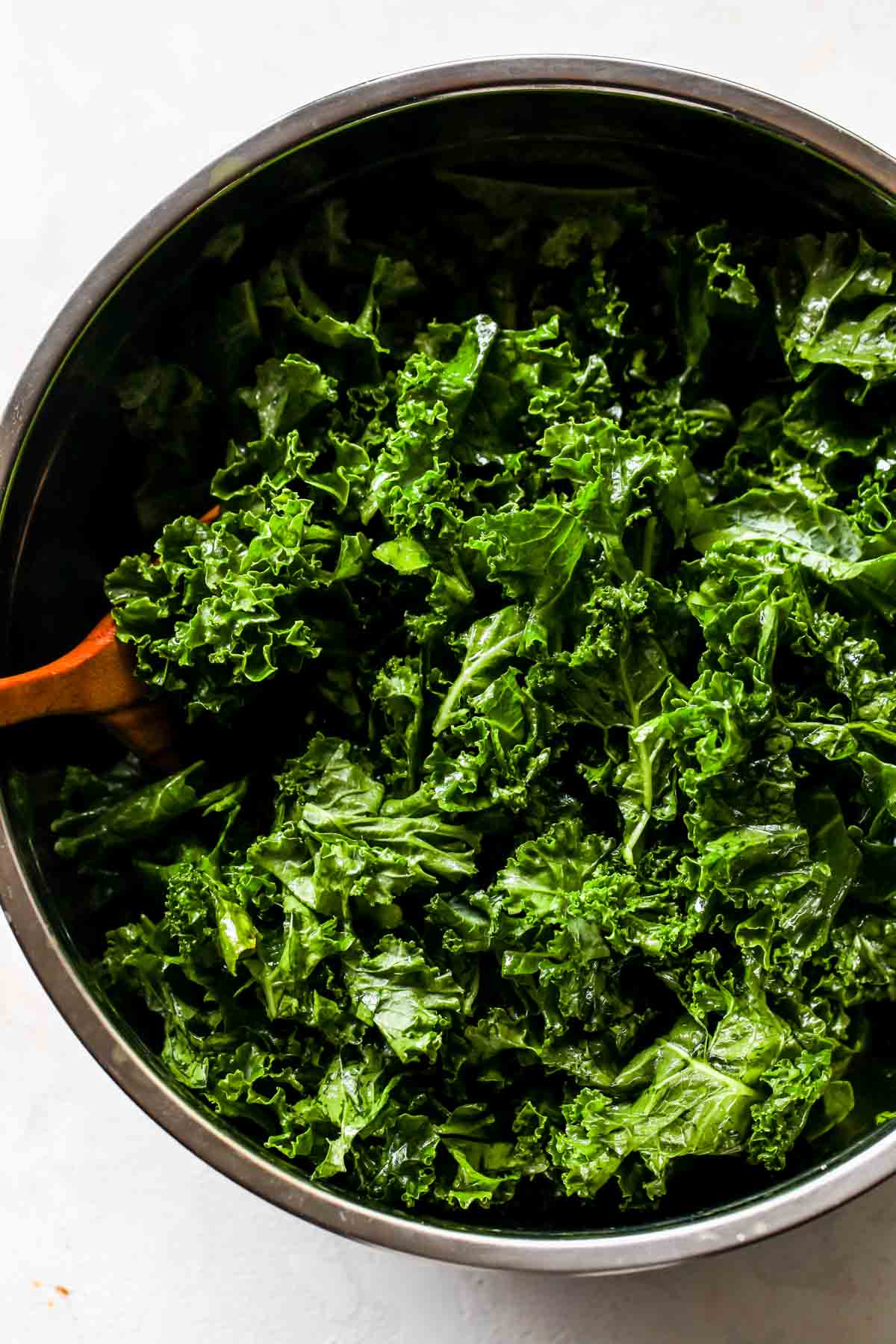 Chopped kale being massaged in a large mixing bowl