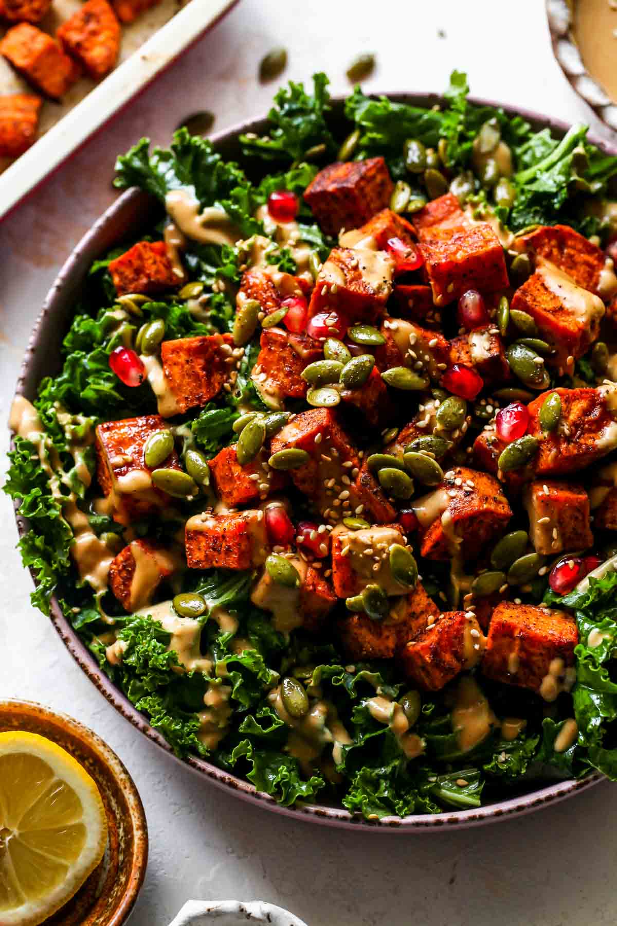 Kale and sweet potato salad on a platter topped with pomegranate and pumpkin seeds