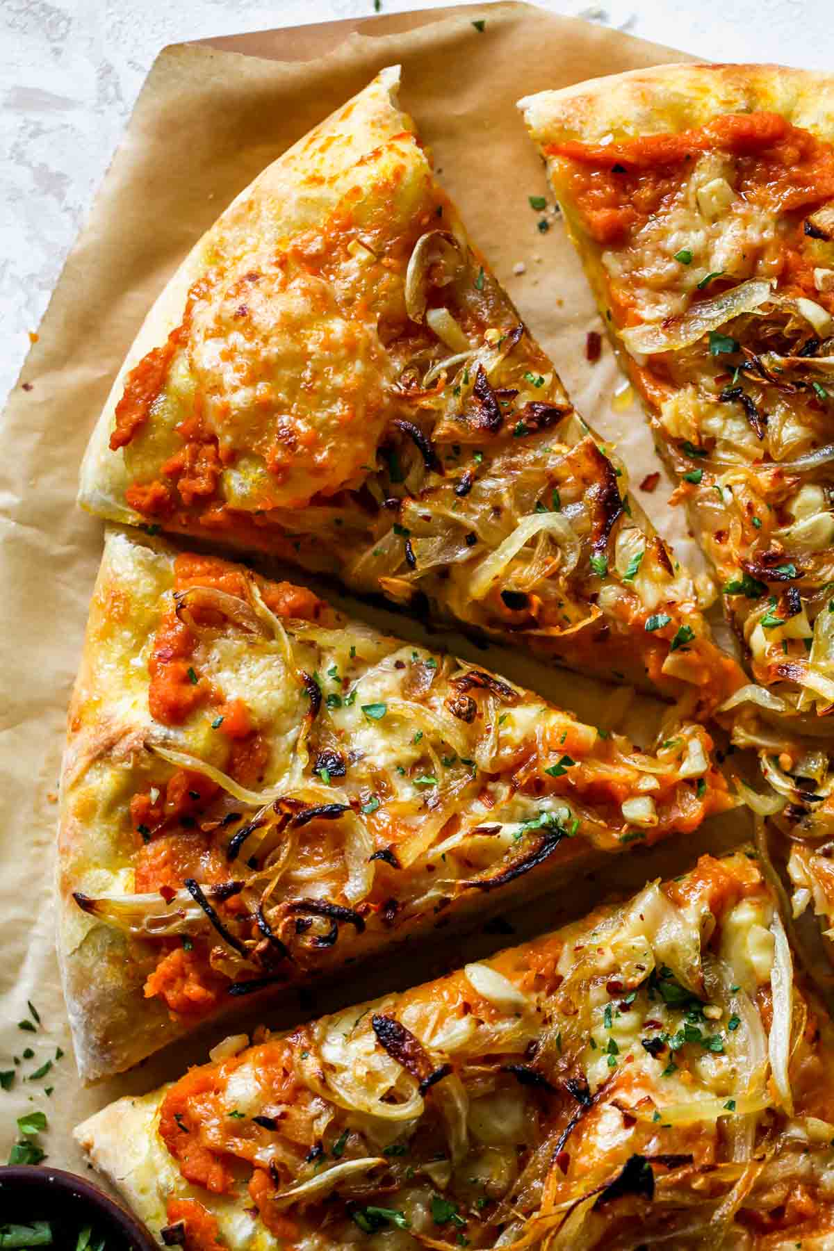 Two slices of pumpkin pizza on a piece of parchment paper