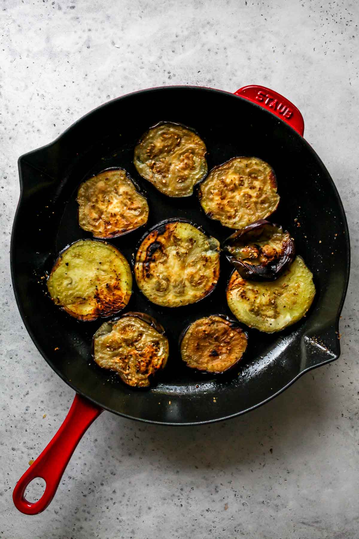 Slices of eggplant being sautéed in a pan