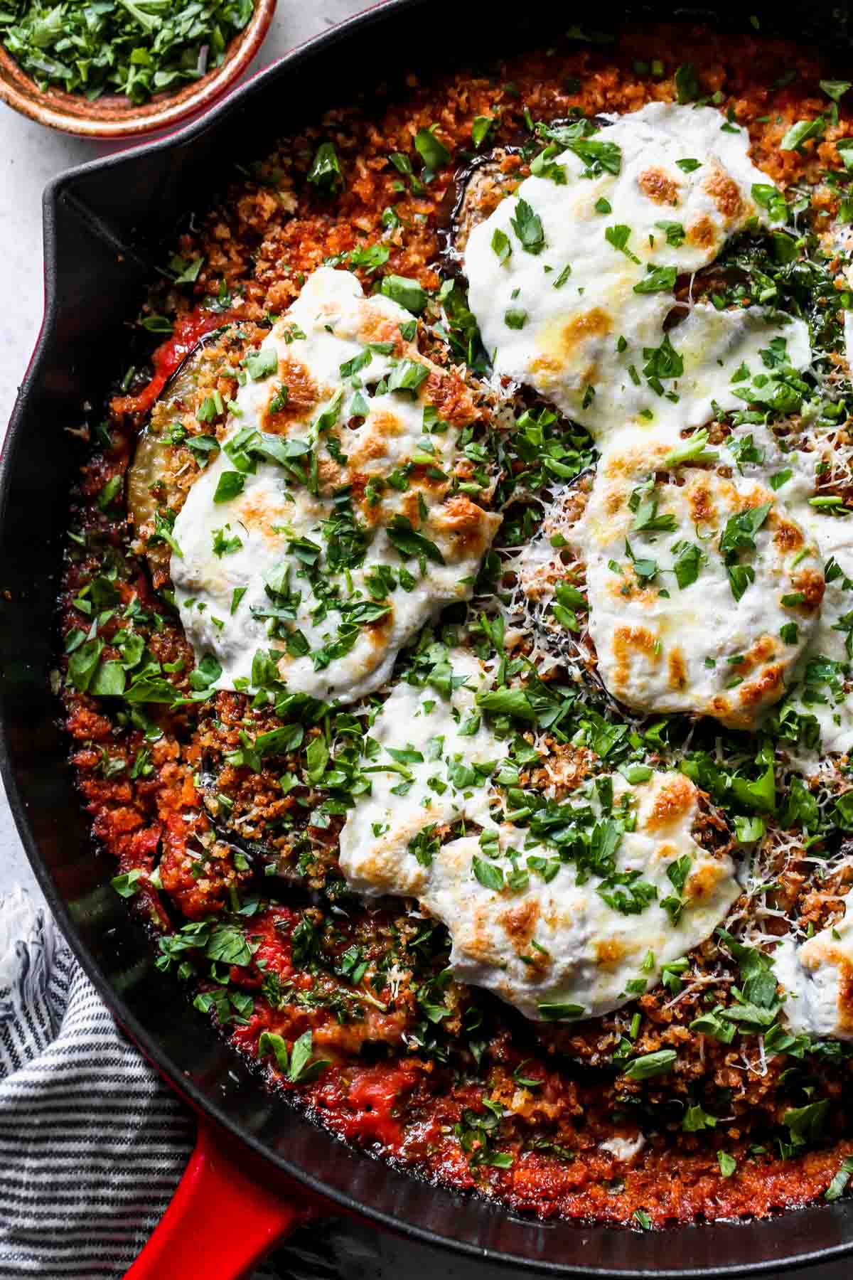 Red pan filled with eggplant, mozzarella, panko, and parsley