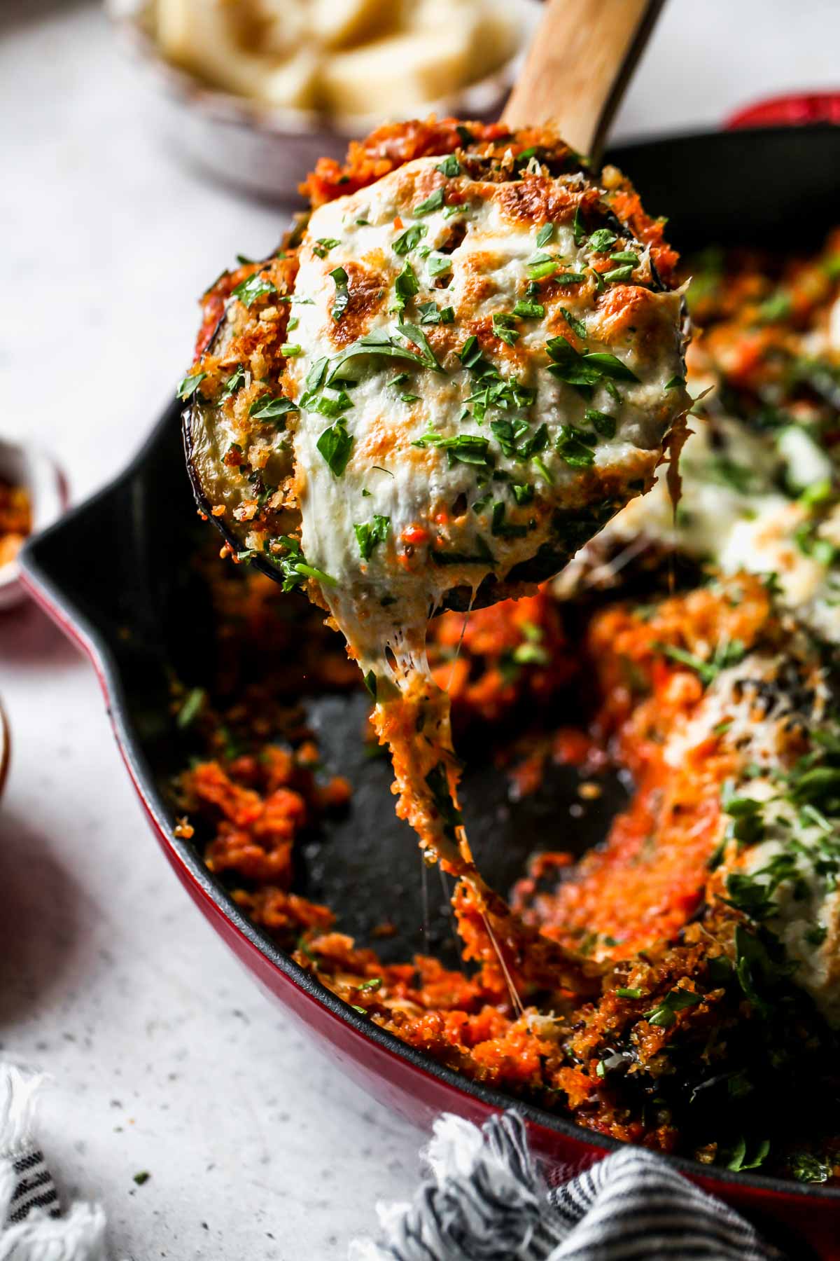Cheesy eggplant being pulled from a skillet