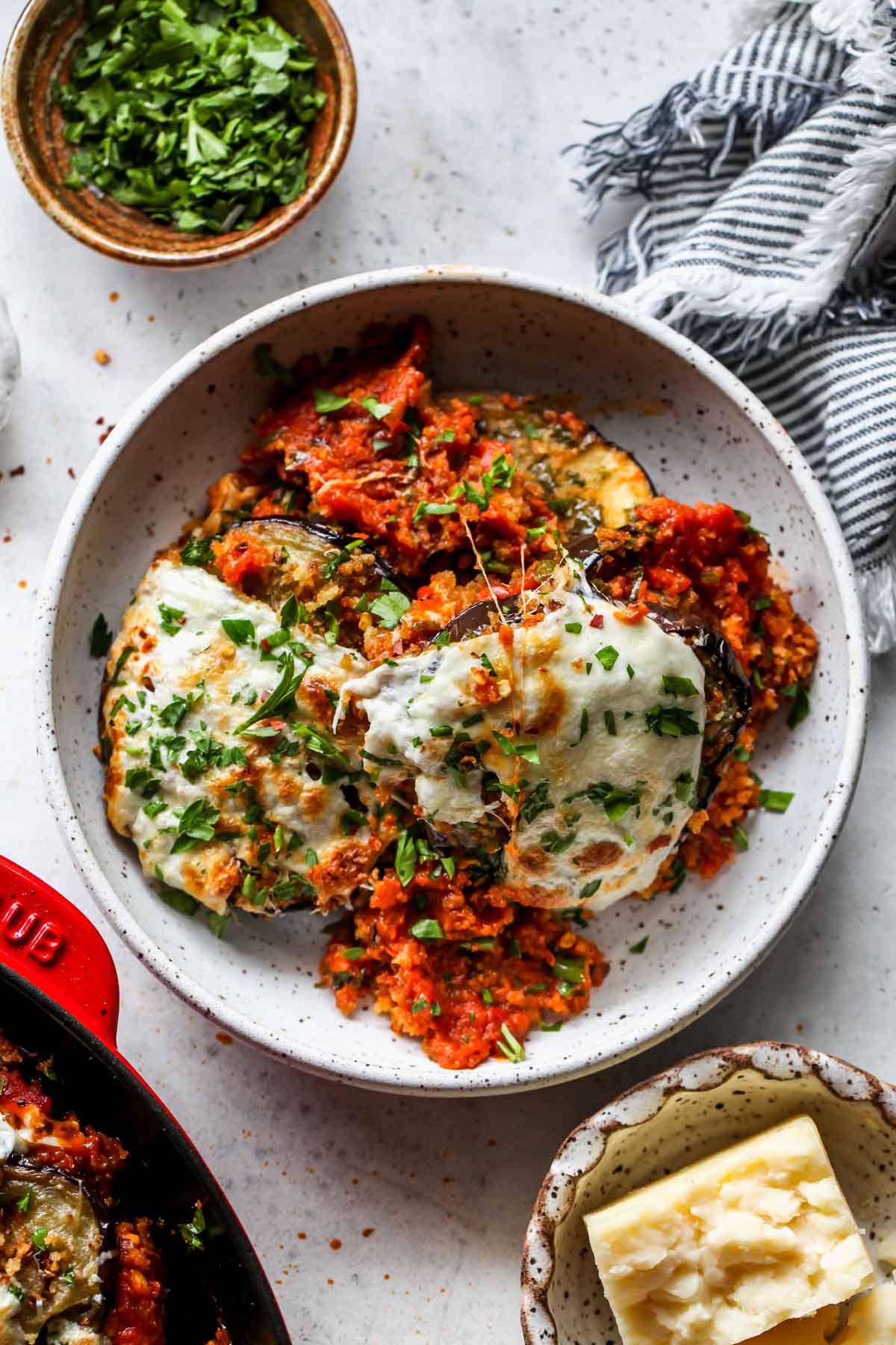 Single serving of eggplant parm in a white bowl topped with parsley
