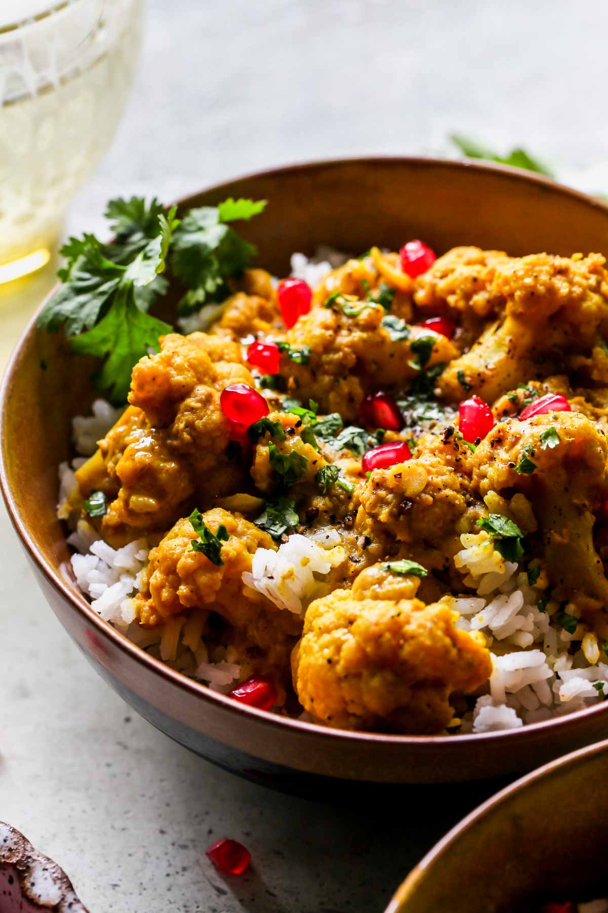 Bowl of lentil curry topping with pomegranate arils and cilantro