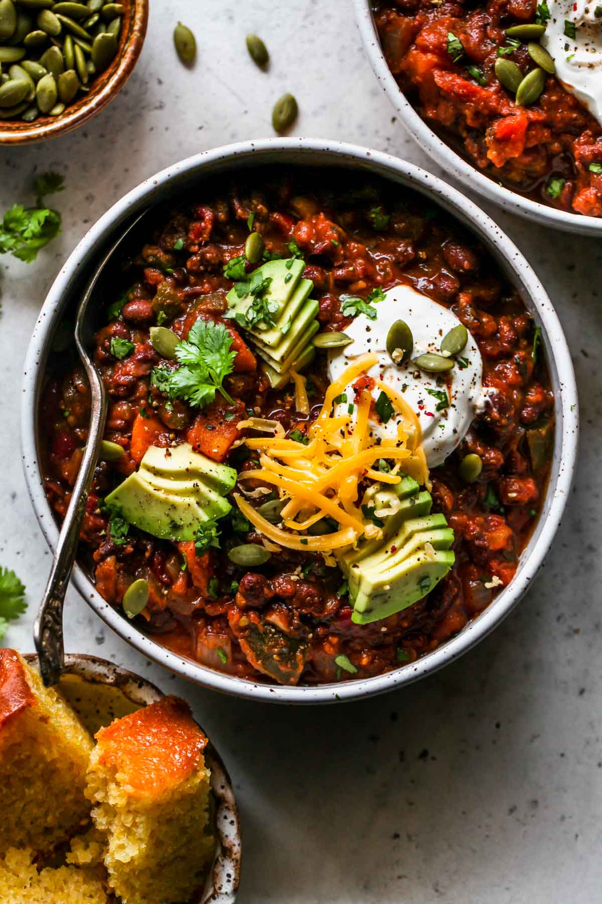 Two bowls of slow cooker vegetarian chili topped with avocado slices