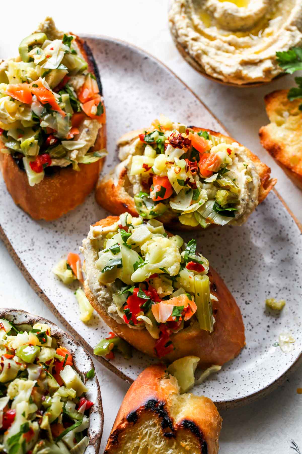Toasted baguettes topped with hummus and artichoke salad