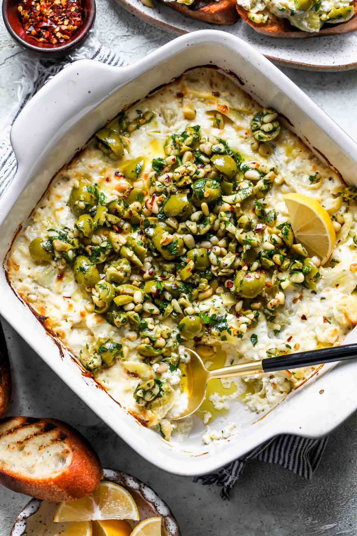 A spoon digging into a pan of cheesy baked cheese dip