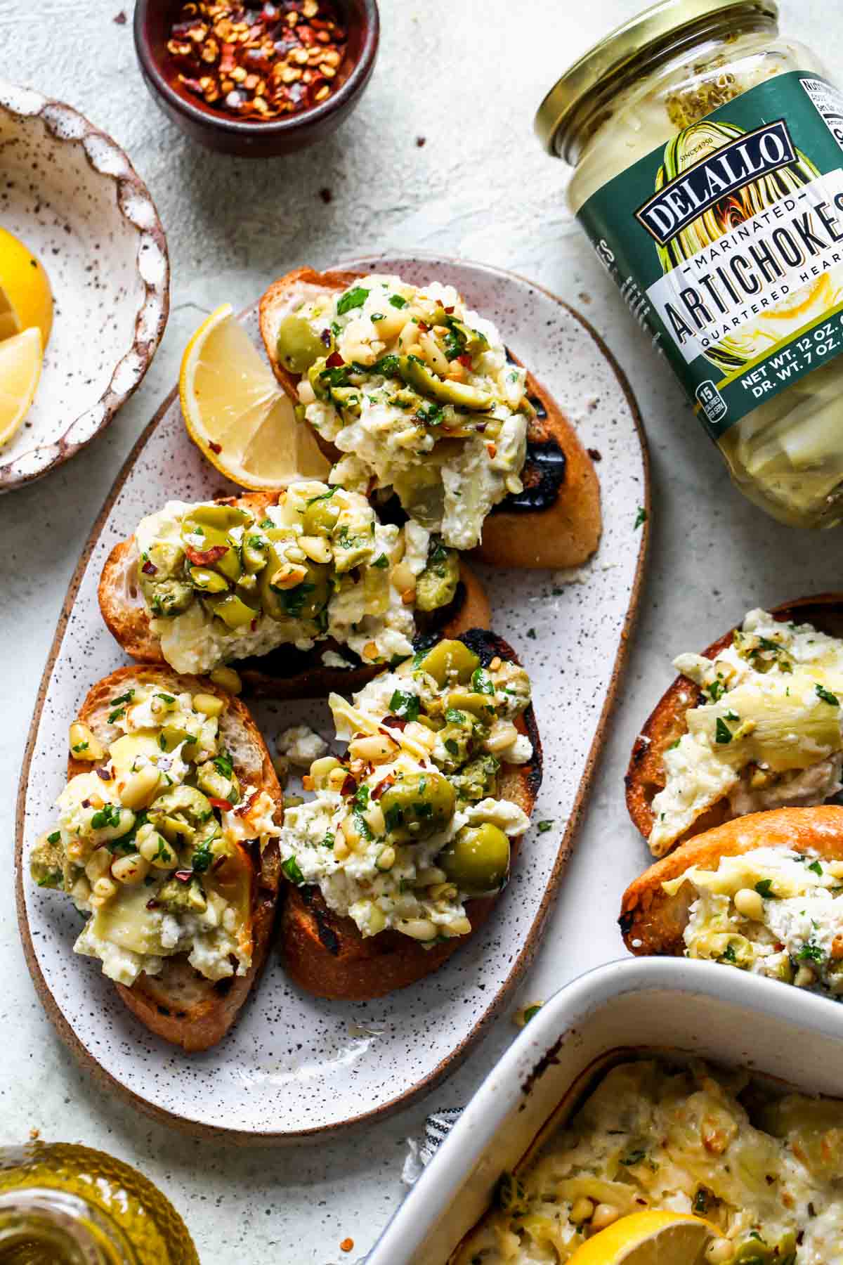 Crostinis topped with artichoke and feta dip on a serving platter