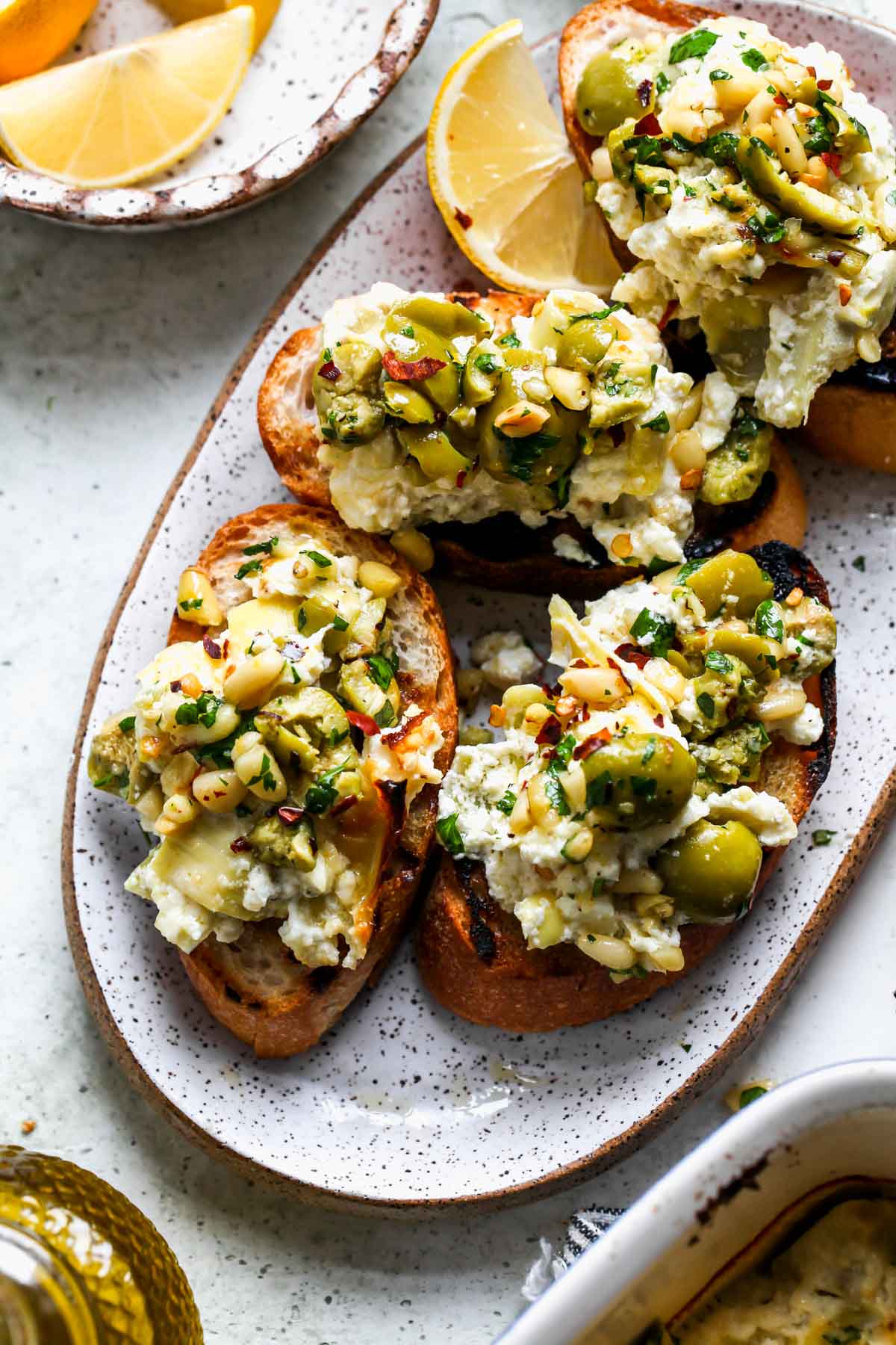 Crostinis topped with feta dip and olives on a platter