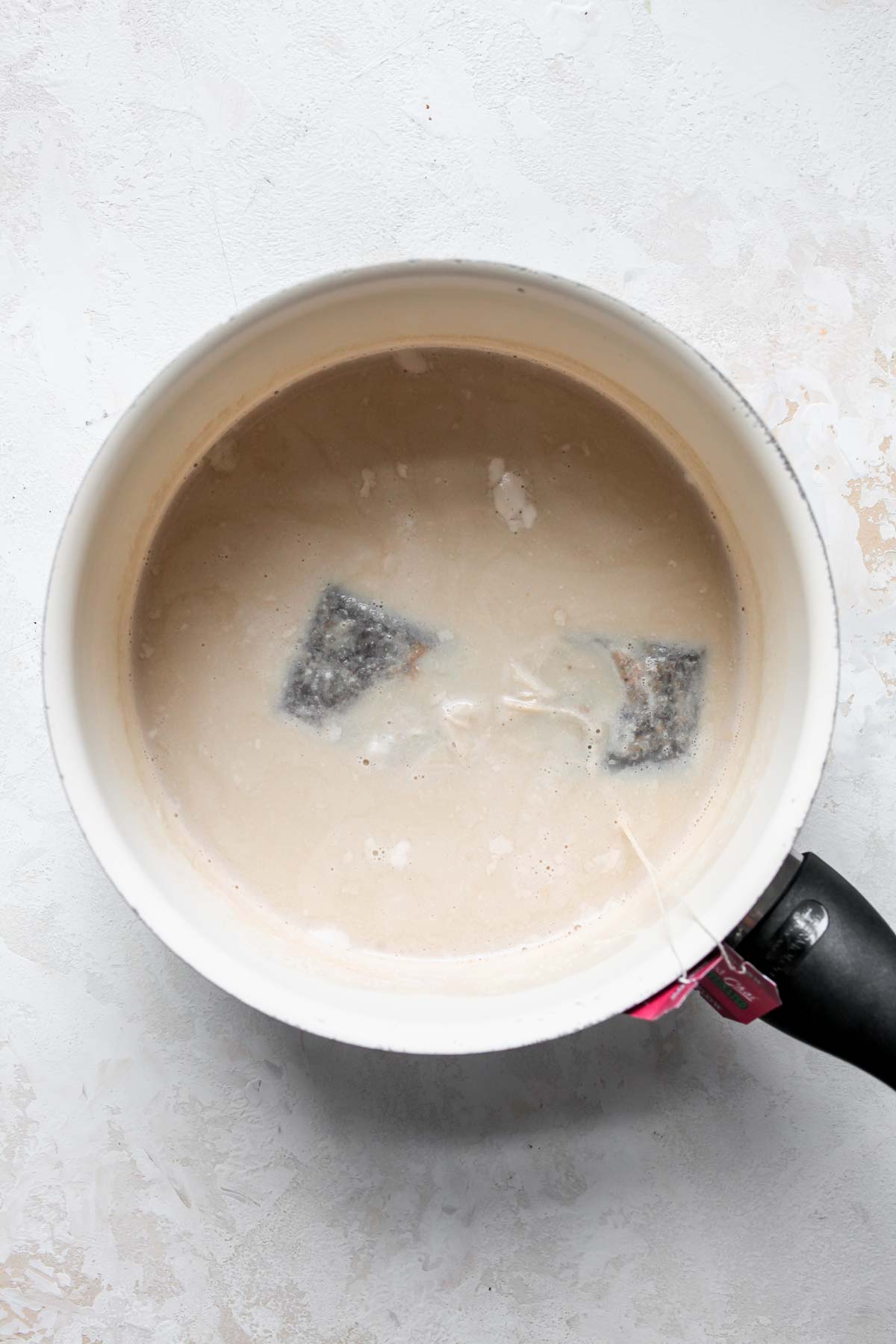 Chai tea bags steeping in a pot of milk