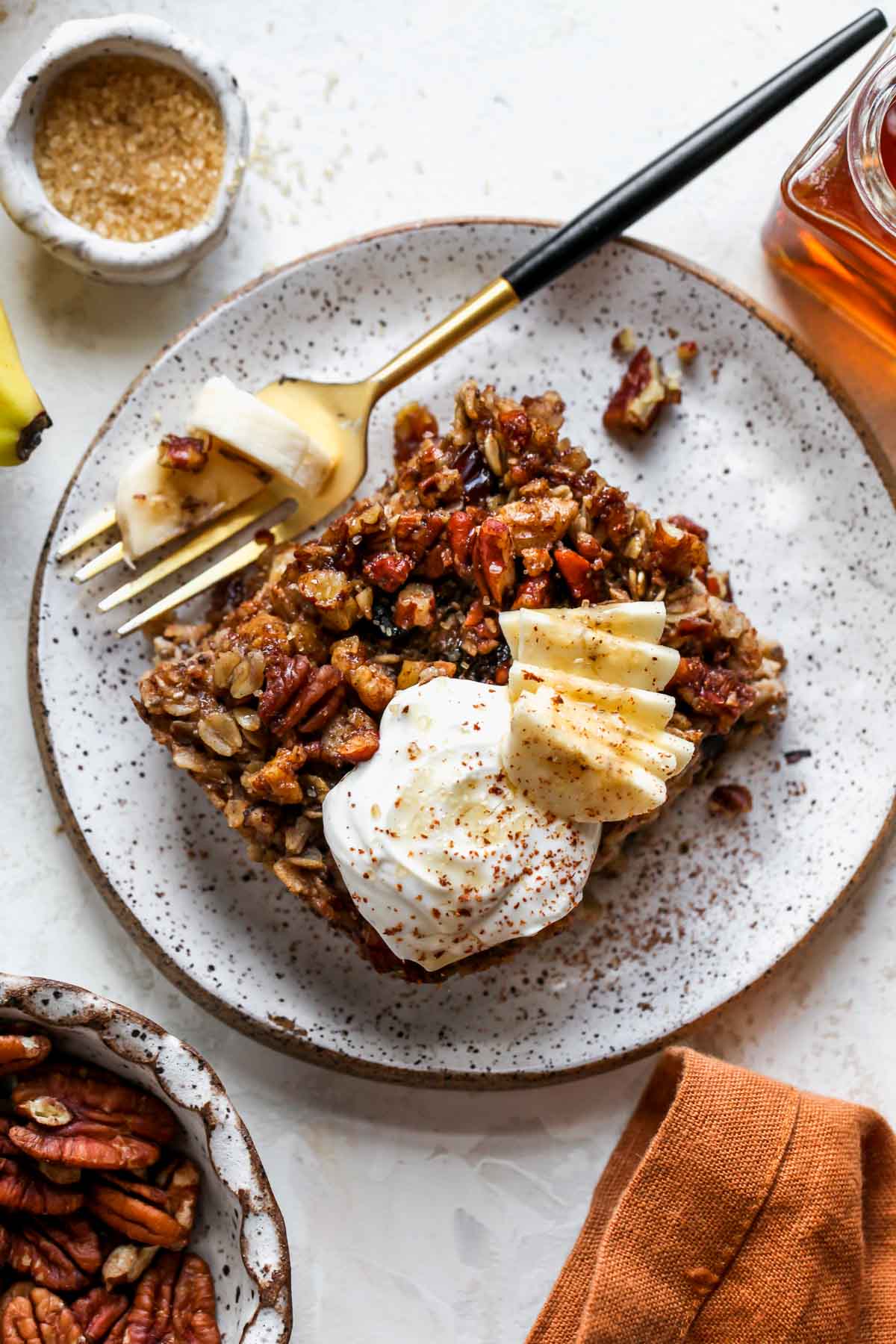 Piece of baked oatmeal on a plate topped with yogurt and banana slices