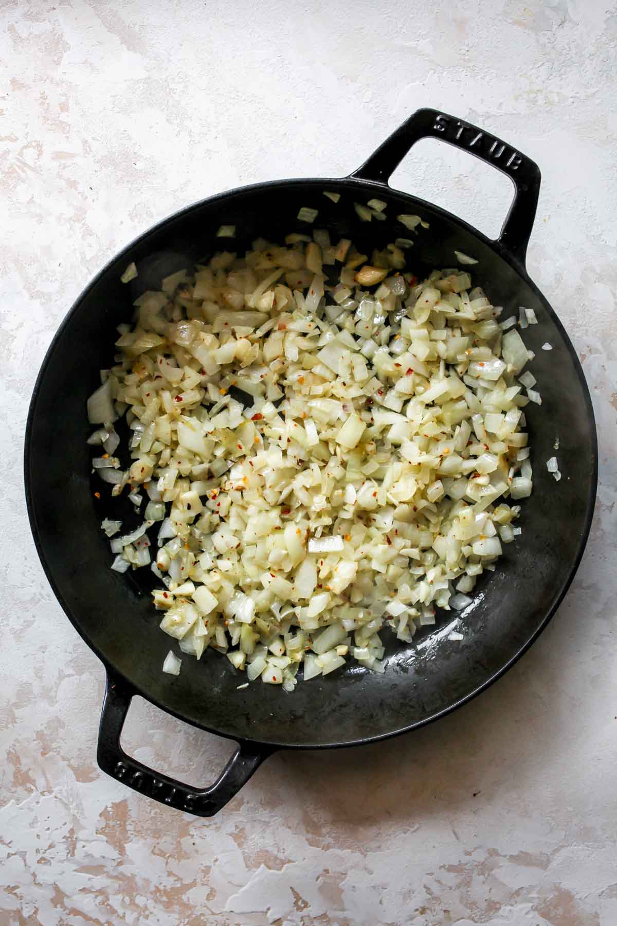 Onions, garlic, and red pepper flakes sautéing in a skillet
