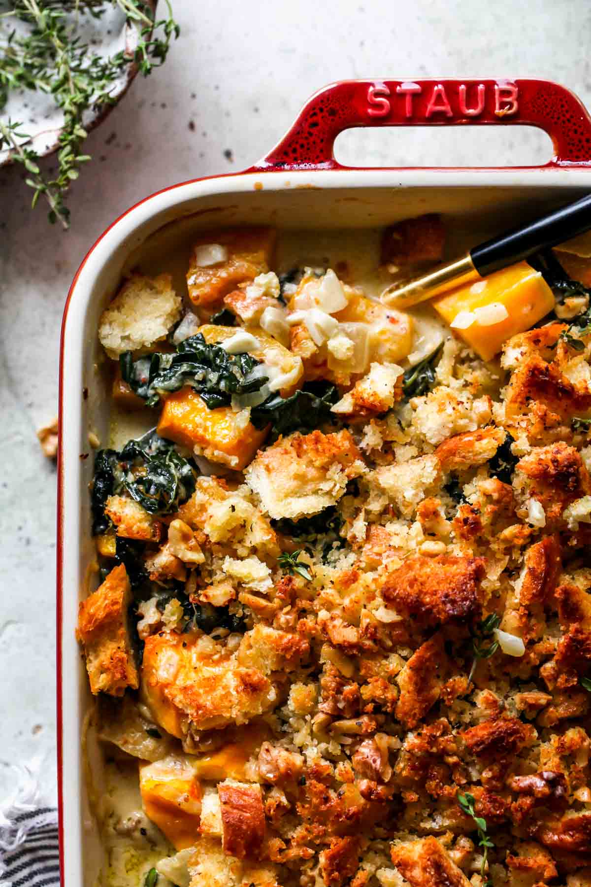 A spoon taking a serving of squash casserole out of a baking dish