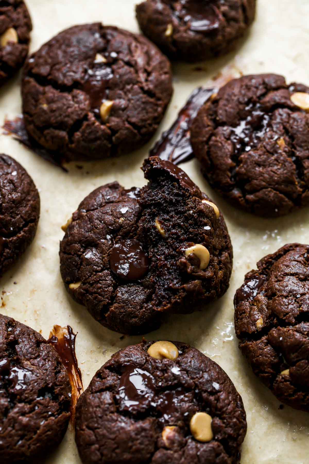 Chocolate cookies on a baking sheet with one broken into to see center