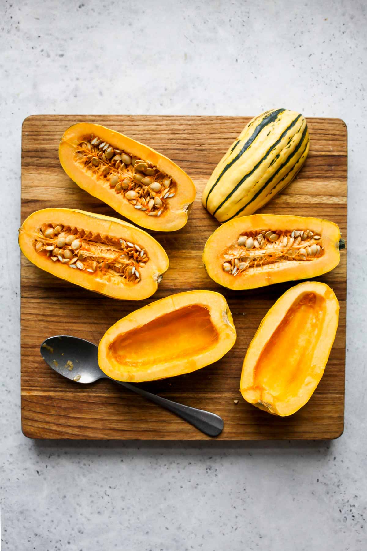 Delicata squash sliced in half on a cutting board