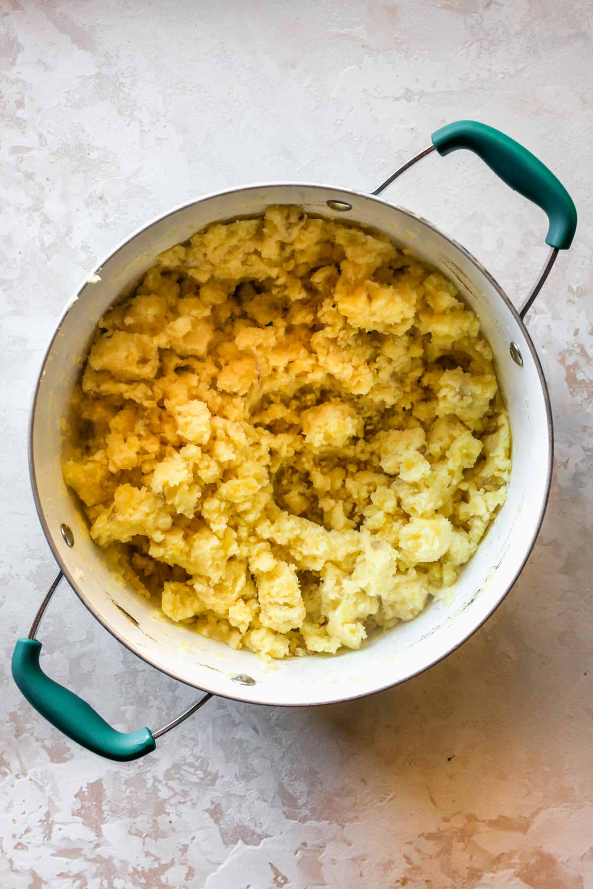 Yukon gold potatoes being mashed in a pot