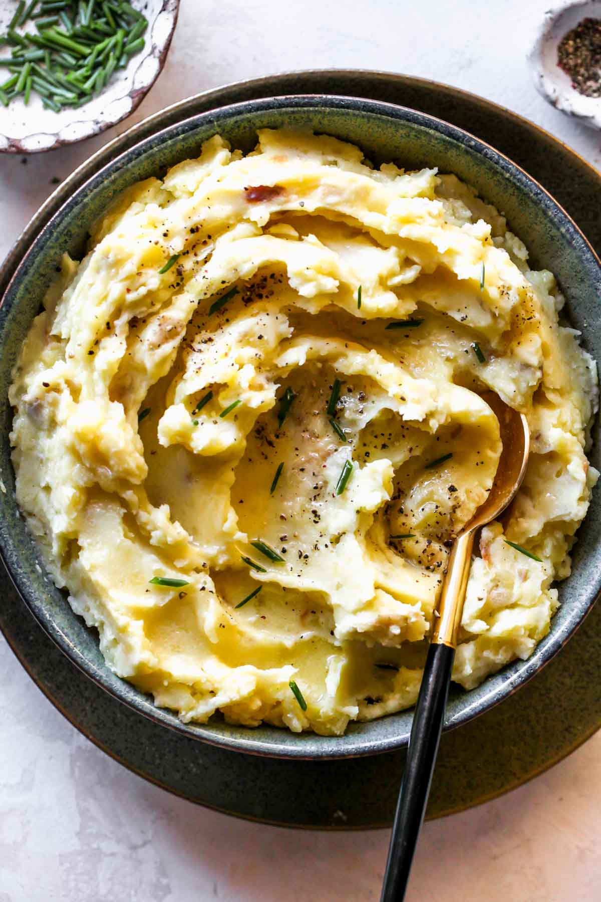 Mashed potatoes in a black bowl with a spoon resting on the side