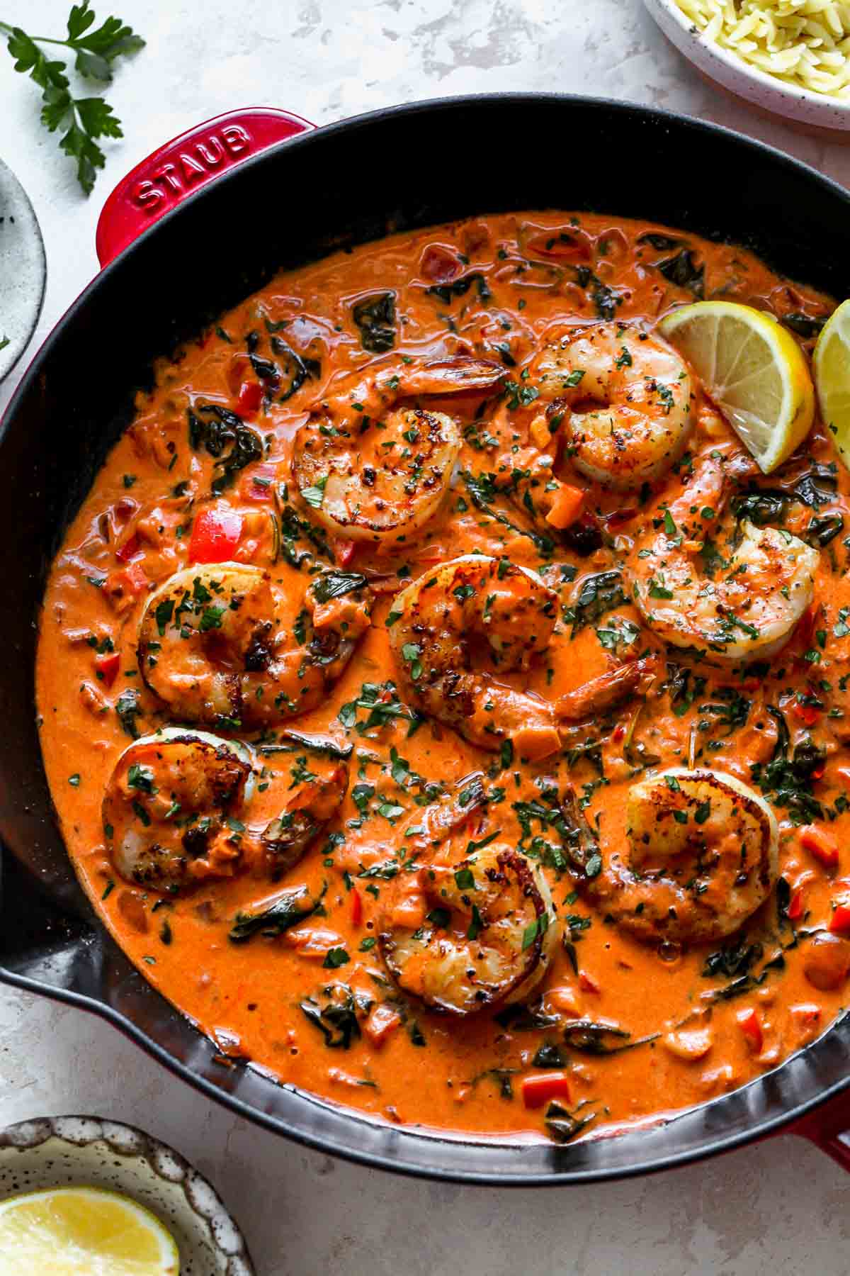 Shrimp in garlic-paprika sauce in a black skillet topped with chopped parsley