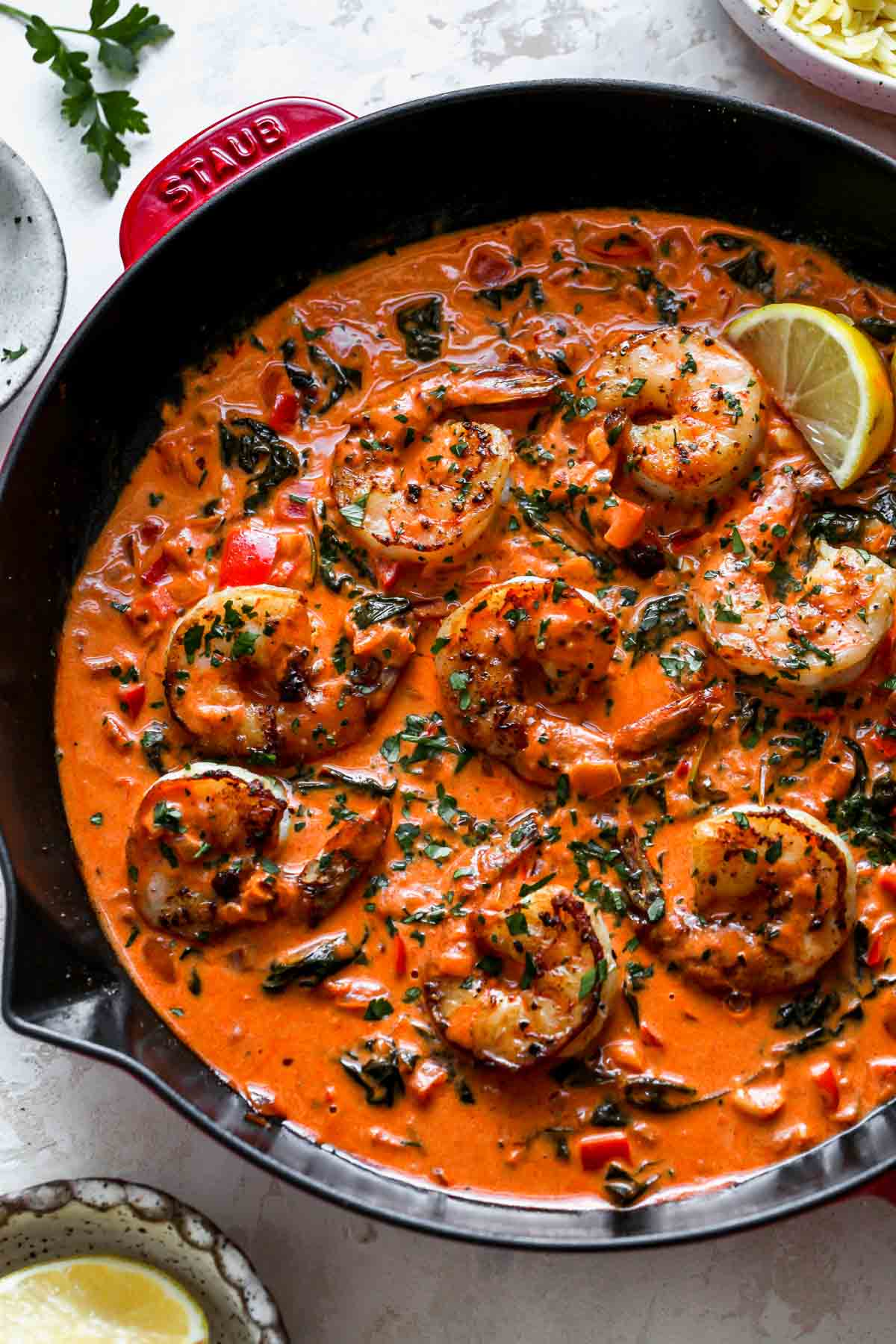 Black skillet filled with sautéed shrimp and creamy red pepper sauce topped with parsley