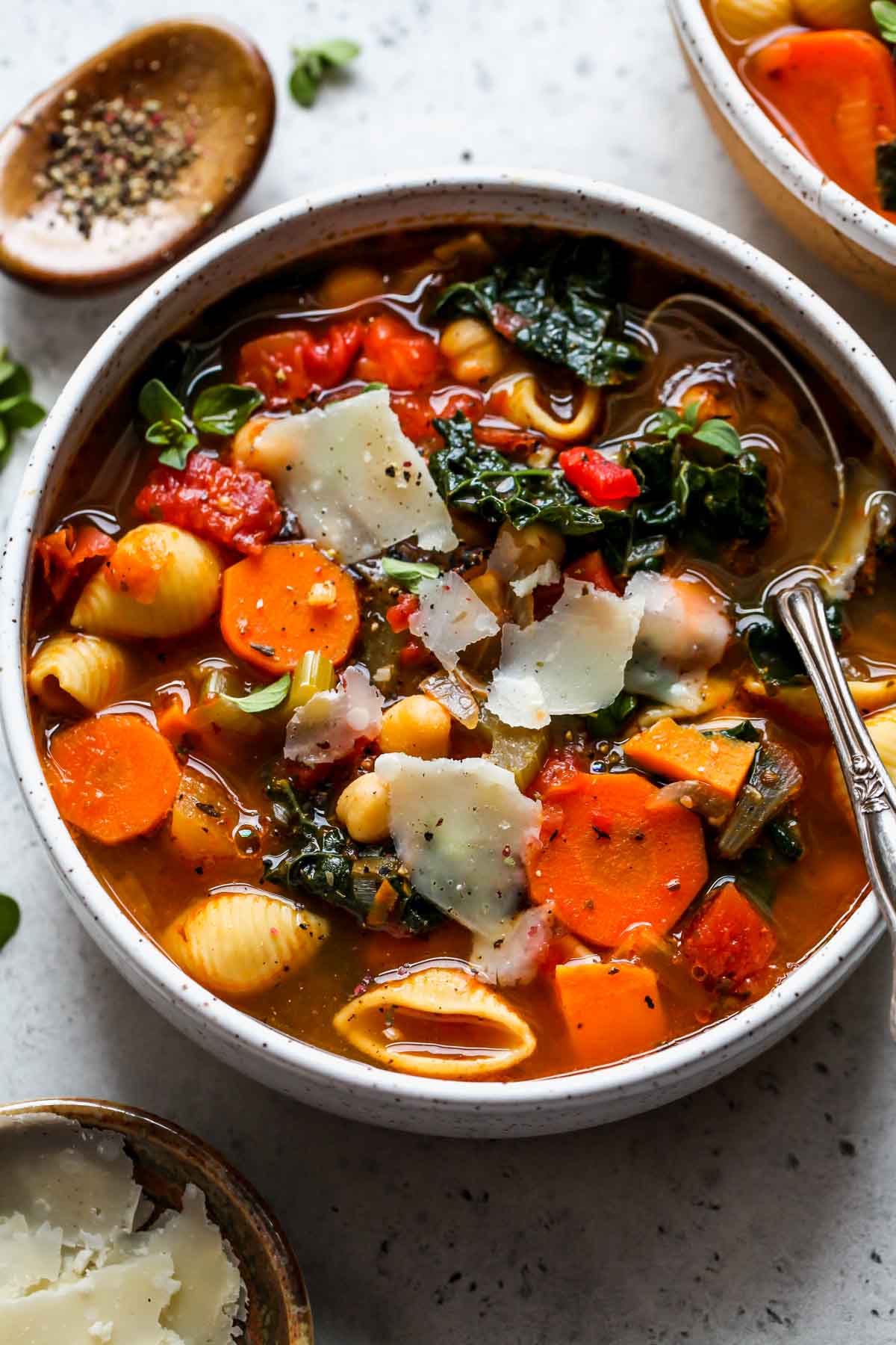 Minestrone soup in a white bowl topped with Parmesan