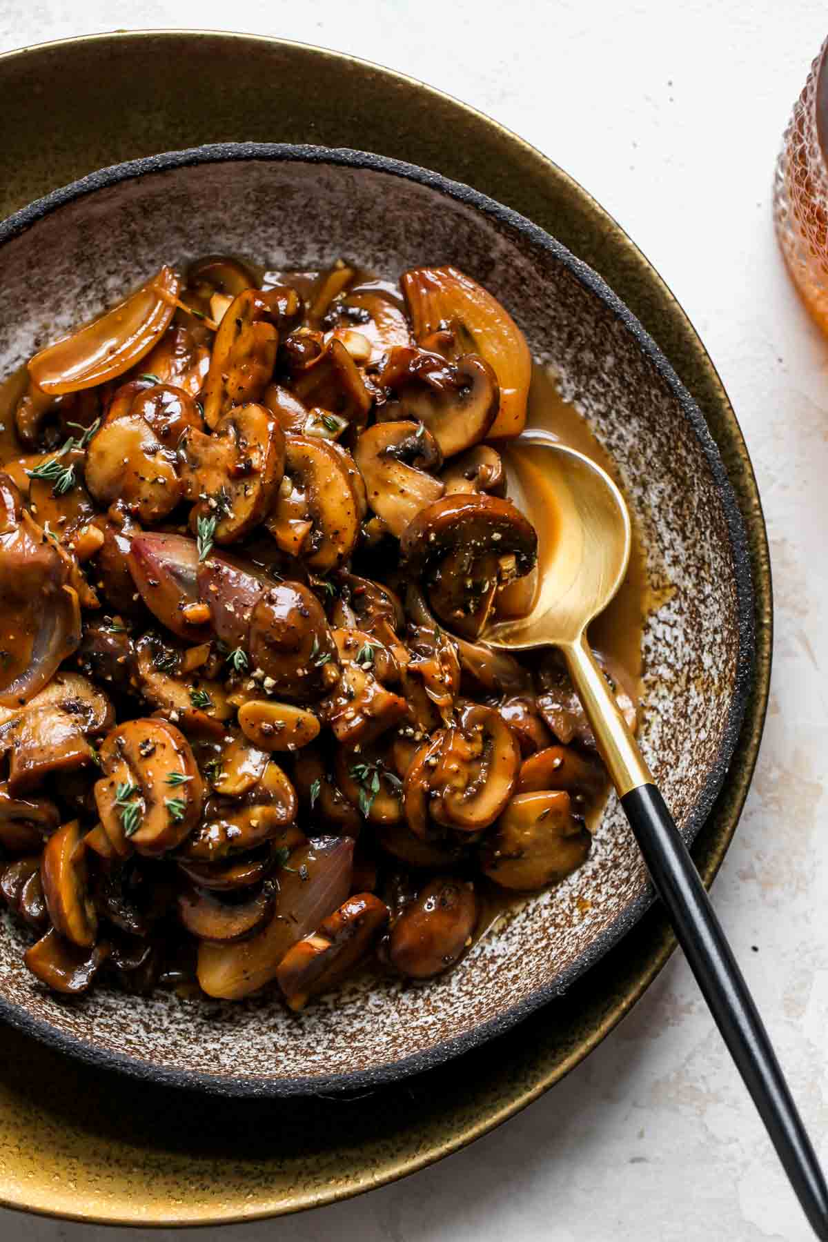 Marsala mushrooms in a bowl with a gold spoon resting on the right side