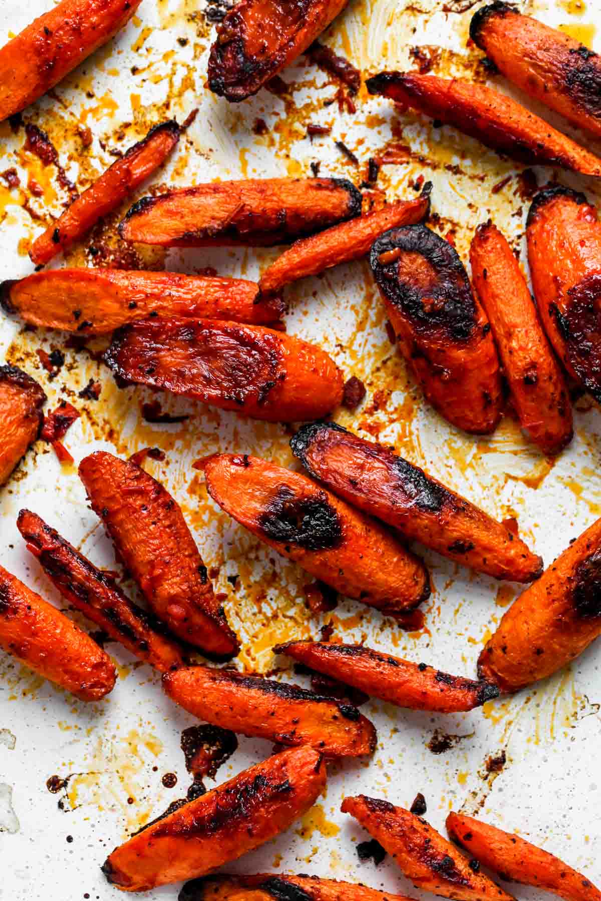 Chunks of roasted carrots on a white rimmed baking sheet