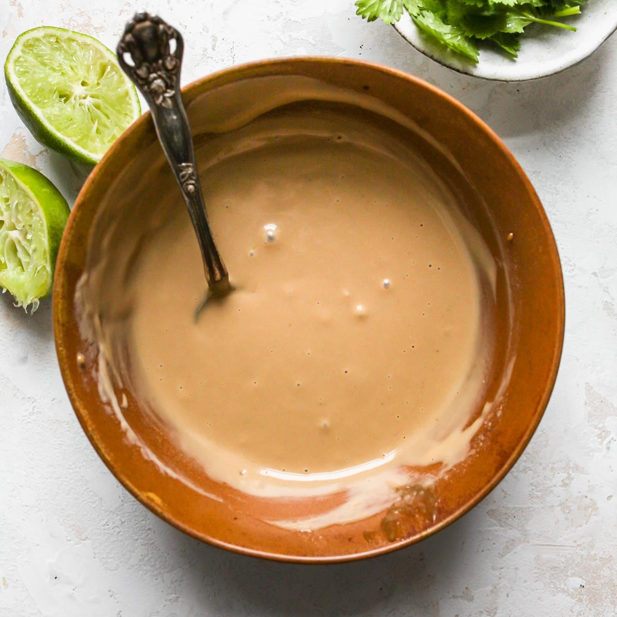 Tahini sauce being whisked in a gold bowl