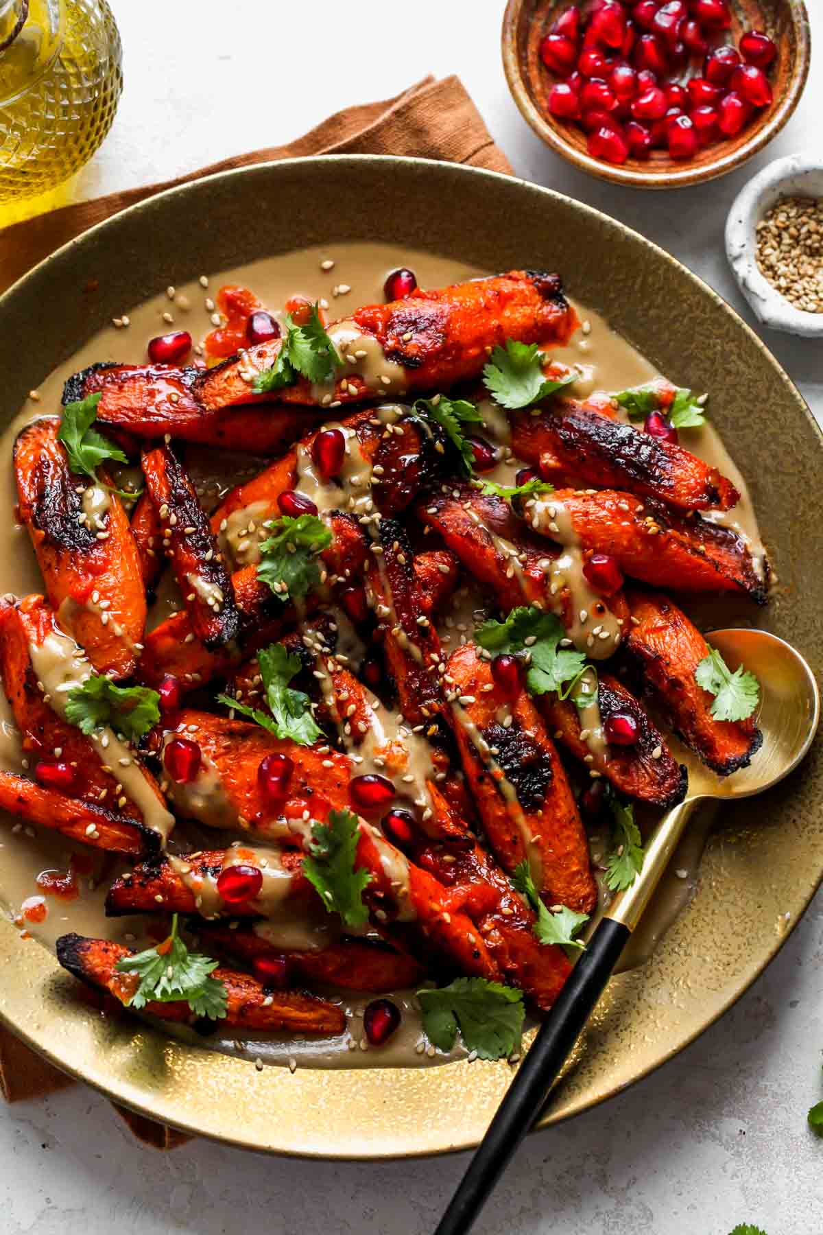Harissa Roasted Carrots on a platter with a serving spoon on the right side