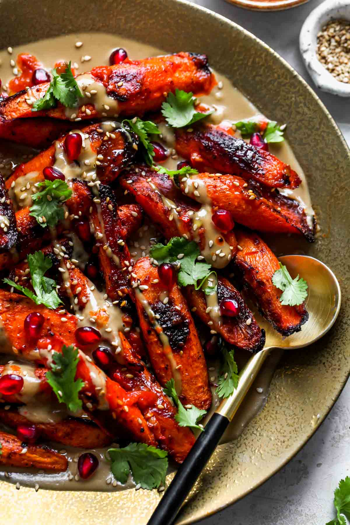 Roasted carrots on a gold plate drizzled with tahini sauce