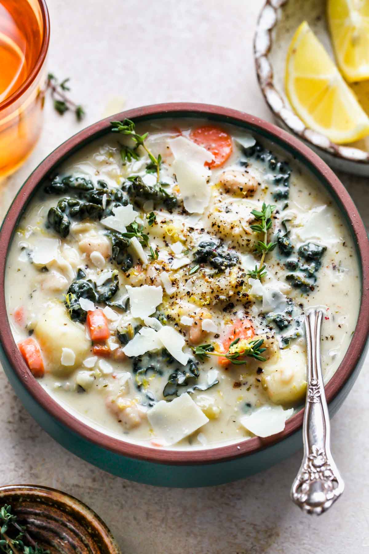 Tuscan gnocchi soup in a bowl topped with Parmesan, herbs, and lemon zest